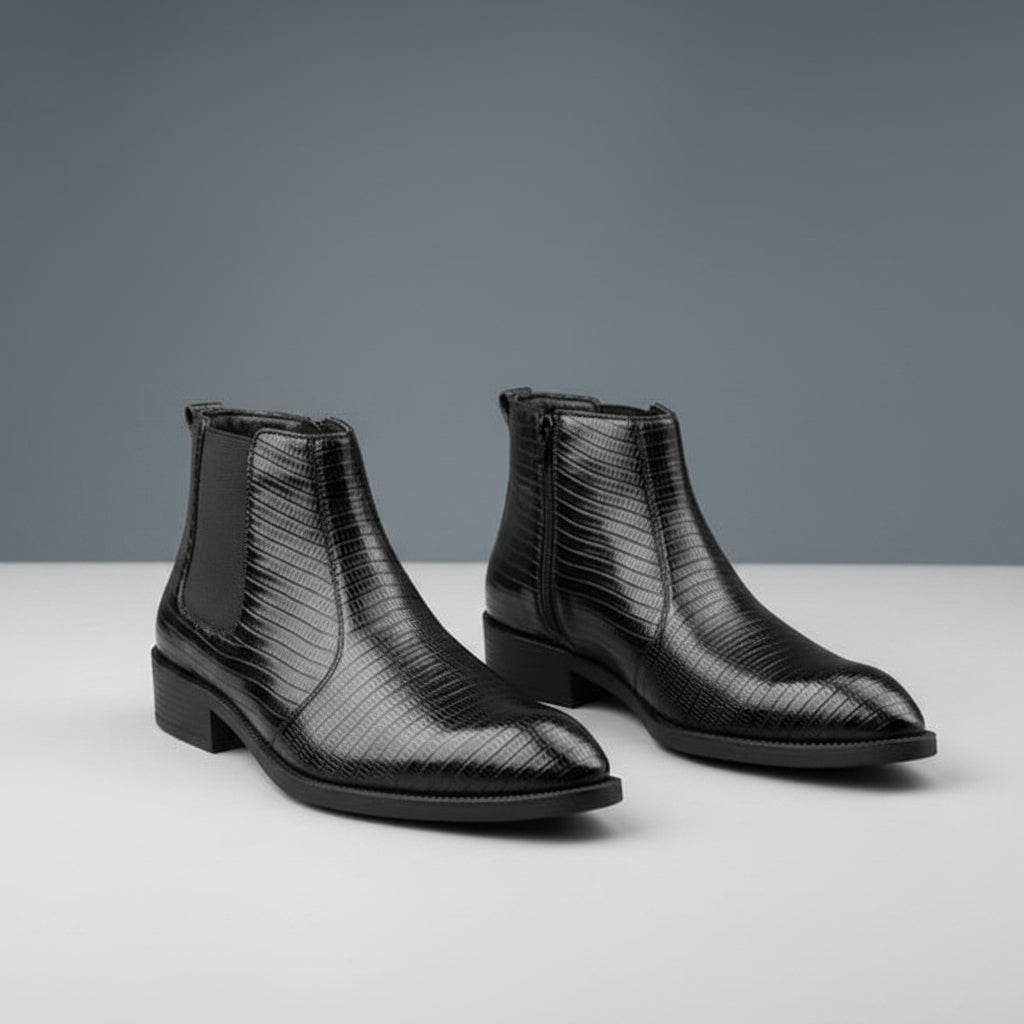 Pair of black textured leather boots on a wooden surface with a gray background