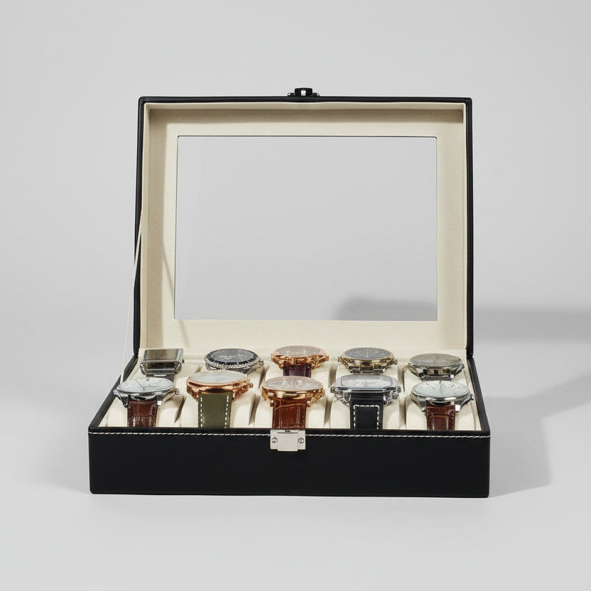 A black watch display case with a clear glass lid, open to show multiple wristwatches inside, set on a table with a blurred Christmas tree and holiday decorations in the background.