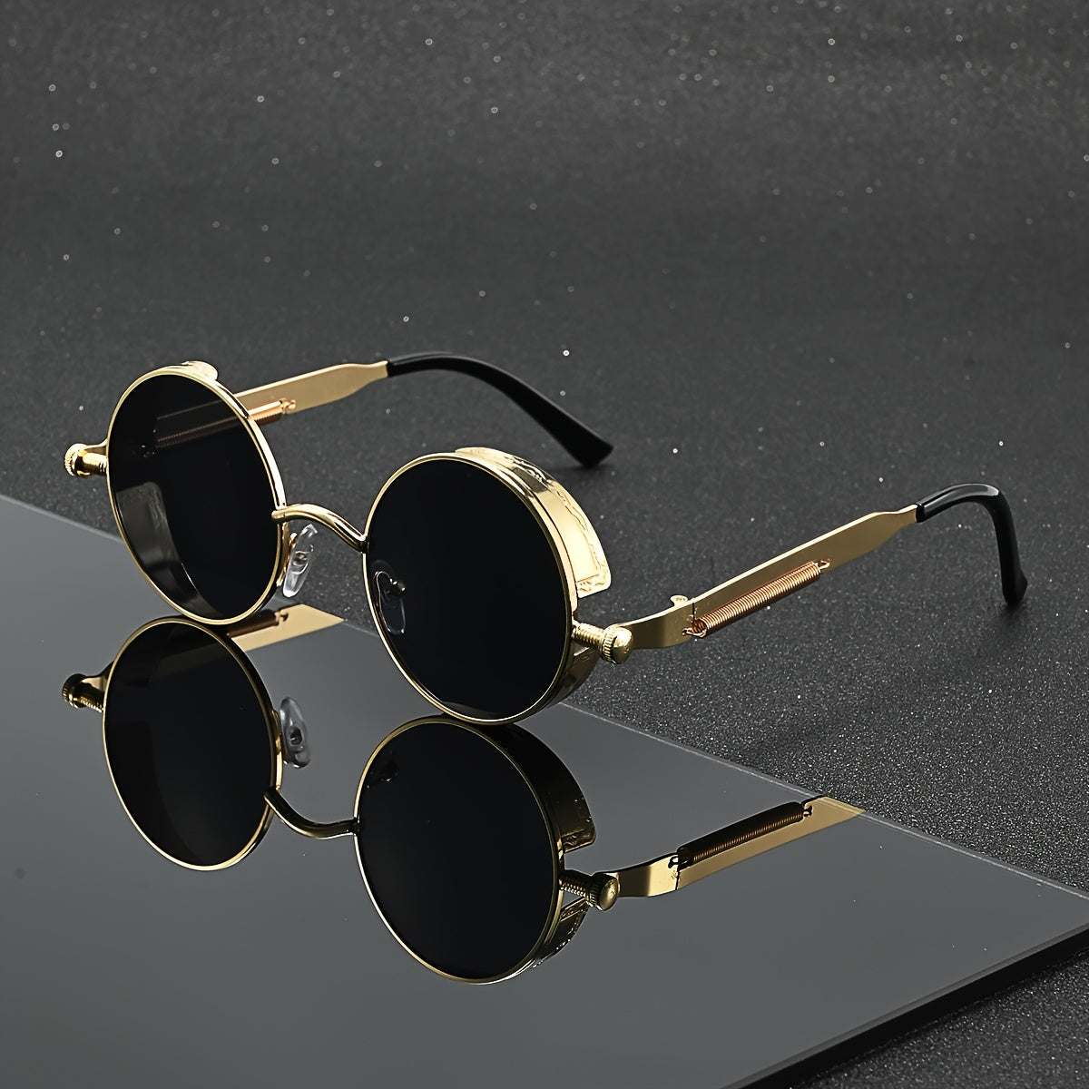 Gold-framed sunglasses with black lenses on a reflective surface.