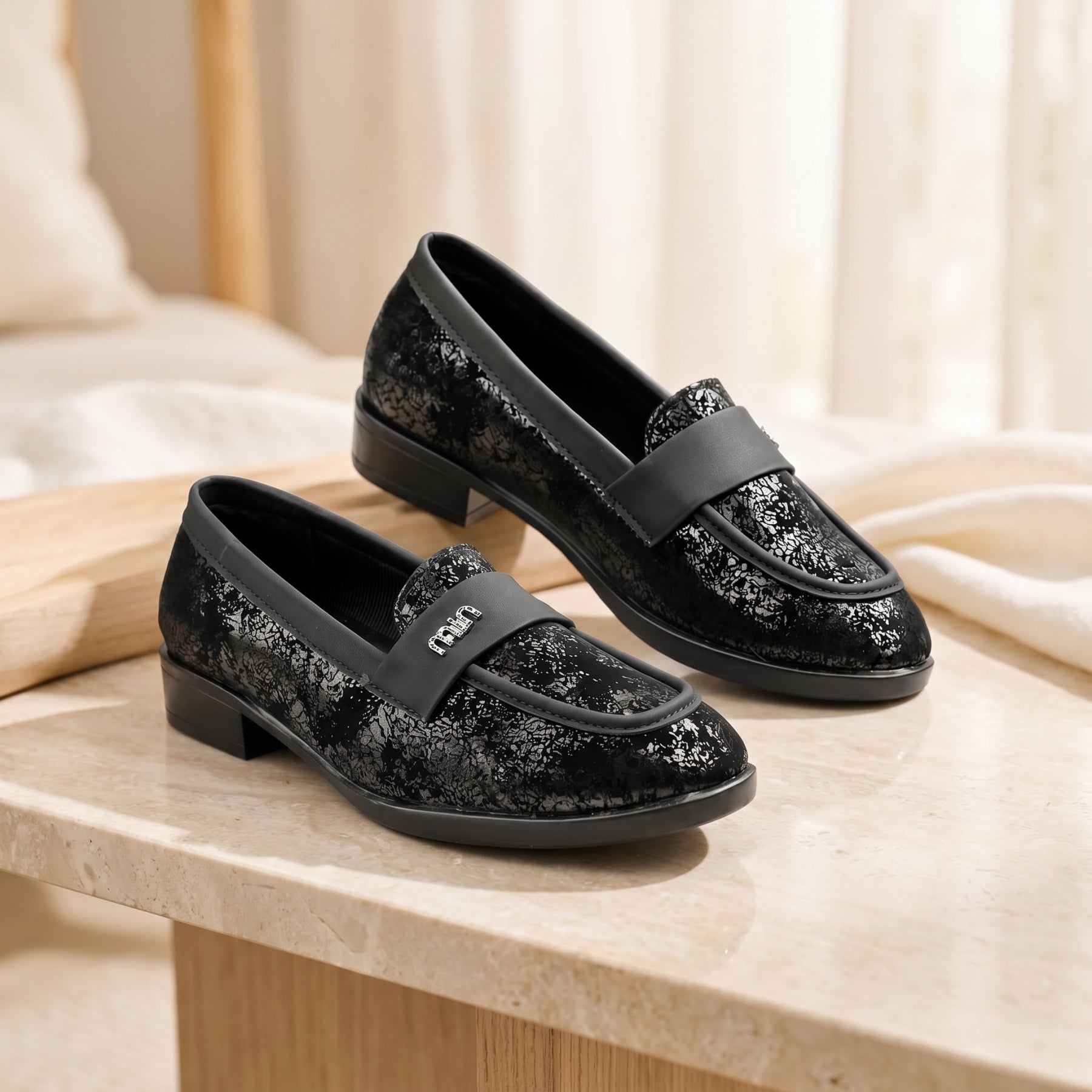 Black glittery loafers on a wooden surface with a soft beige background