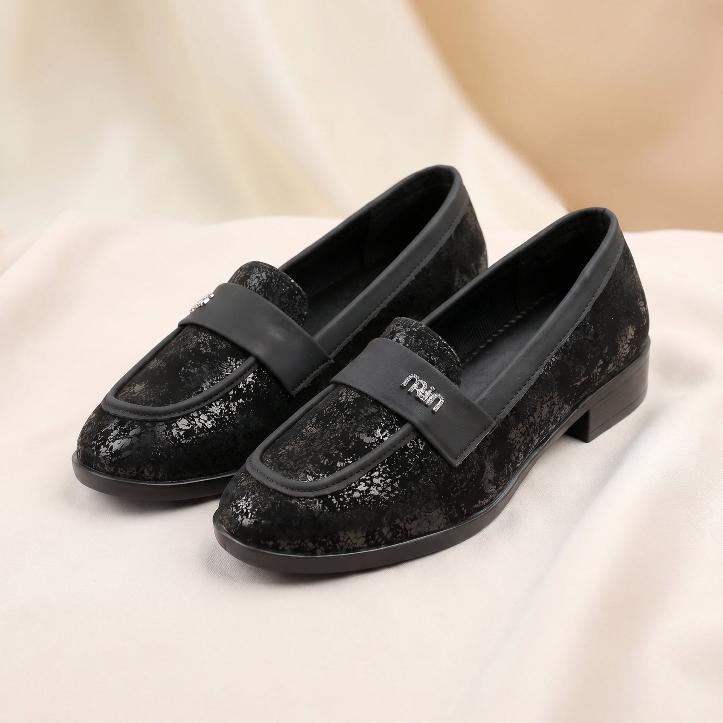 Black glittery loafers with a brand logo on a light background
