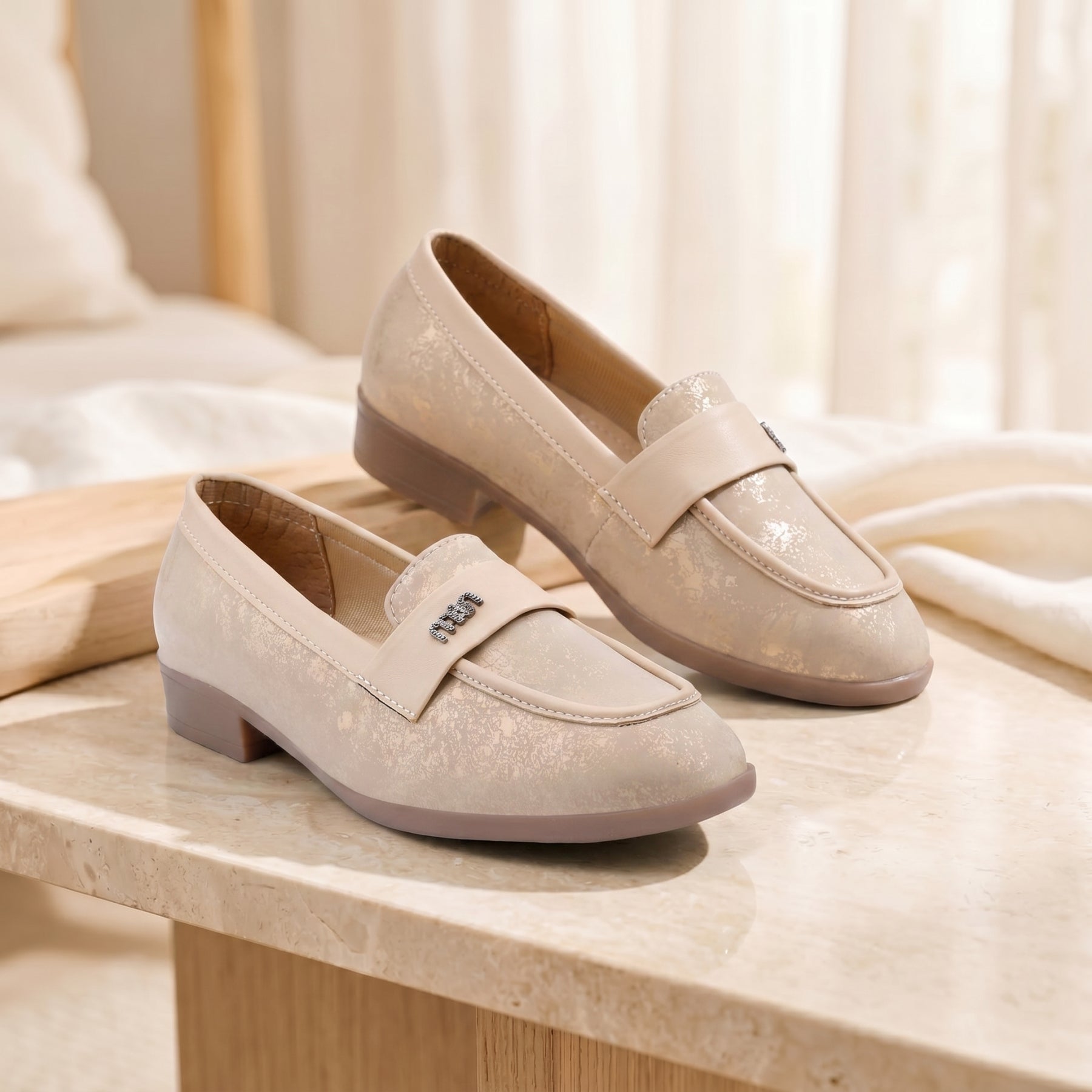 Pair of beige loafers on a light wooden surface with a soft, blurred background