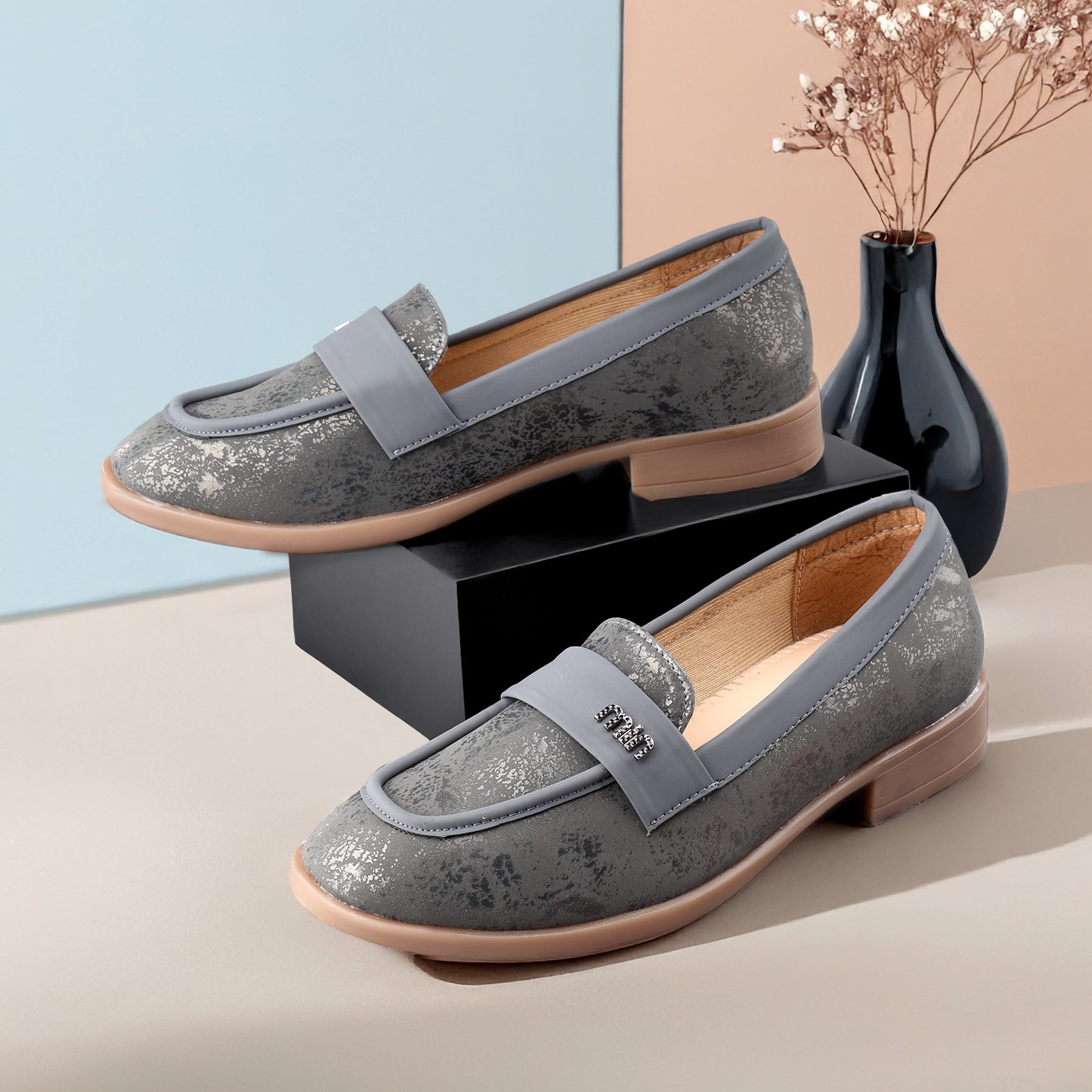 Pair of gray loafers with a decorative bow on a neutral background