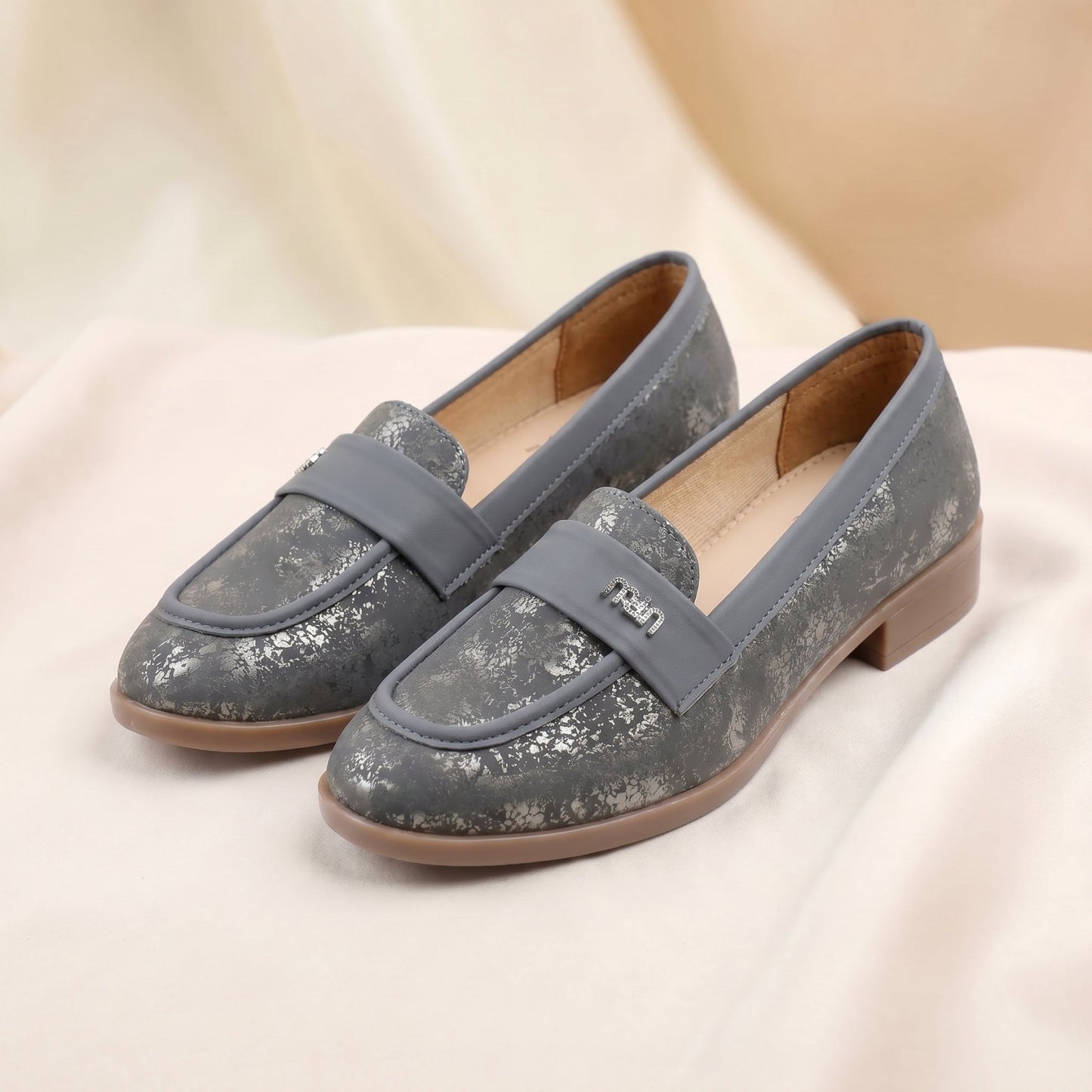 Pair of gray loafers on a light pink fabric background