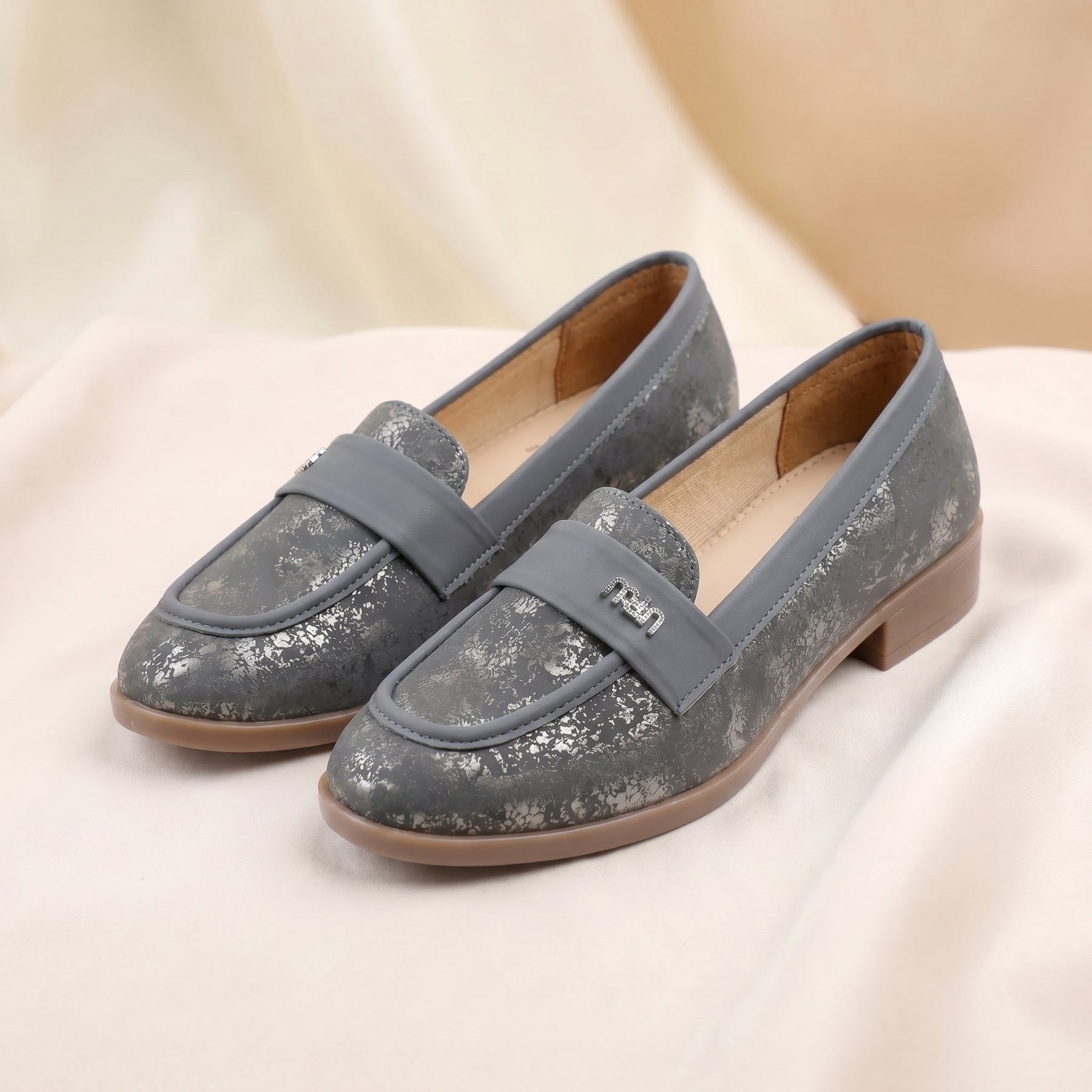 Pair of gray loafers on a light pink fabric background