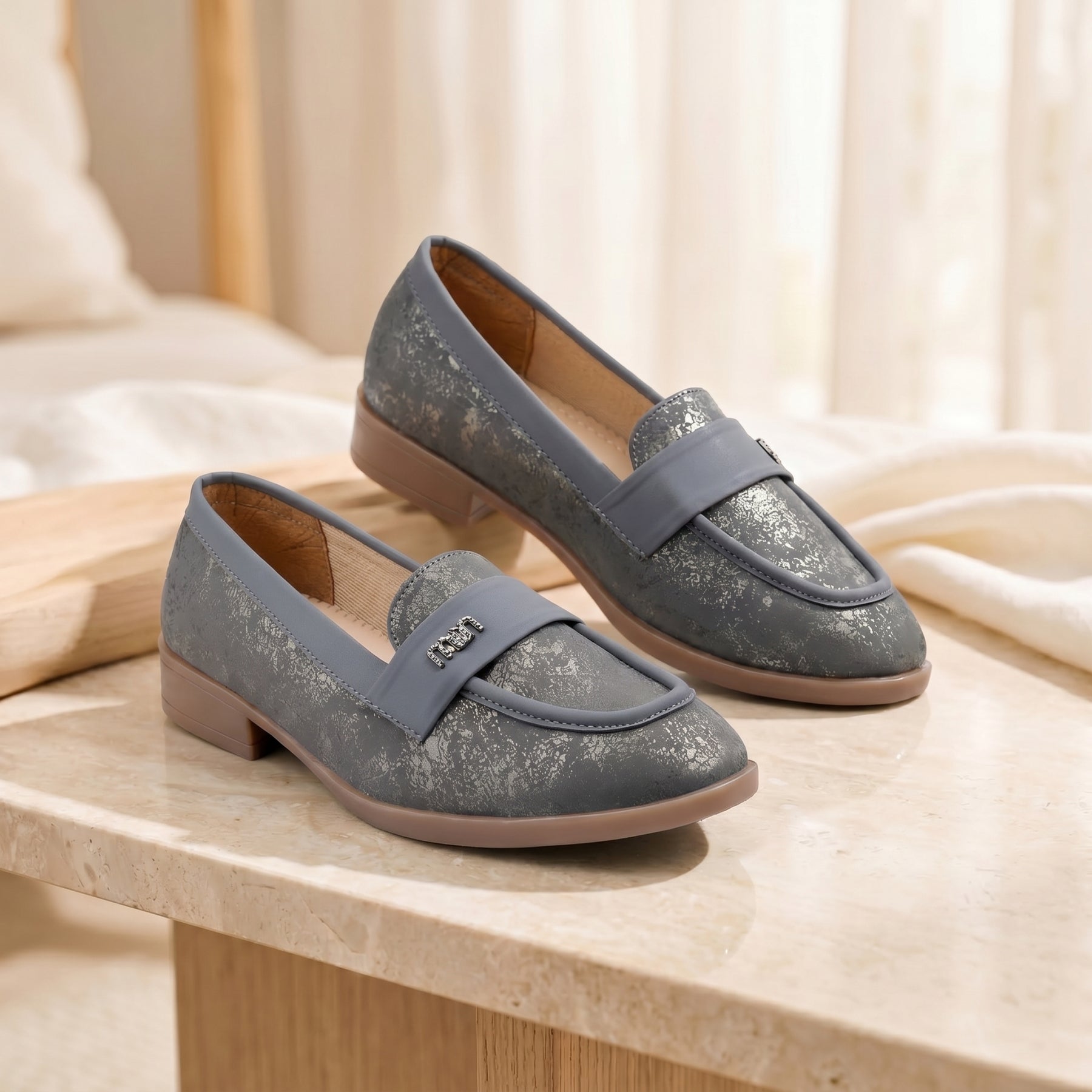 Pair of gray loafers on a light wooden surface with a soft beige background