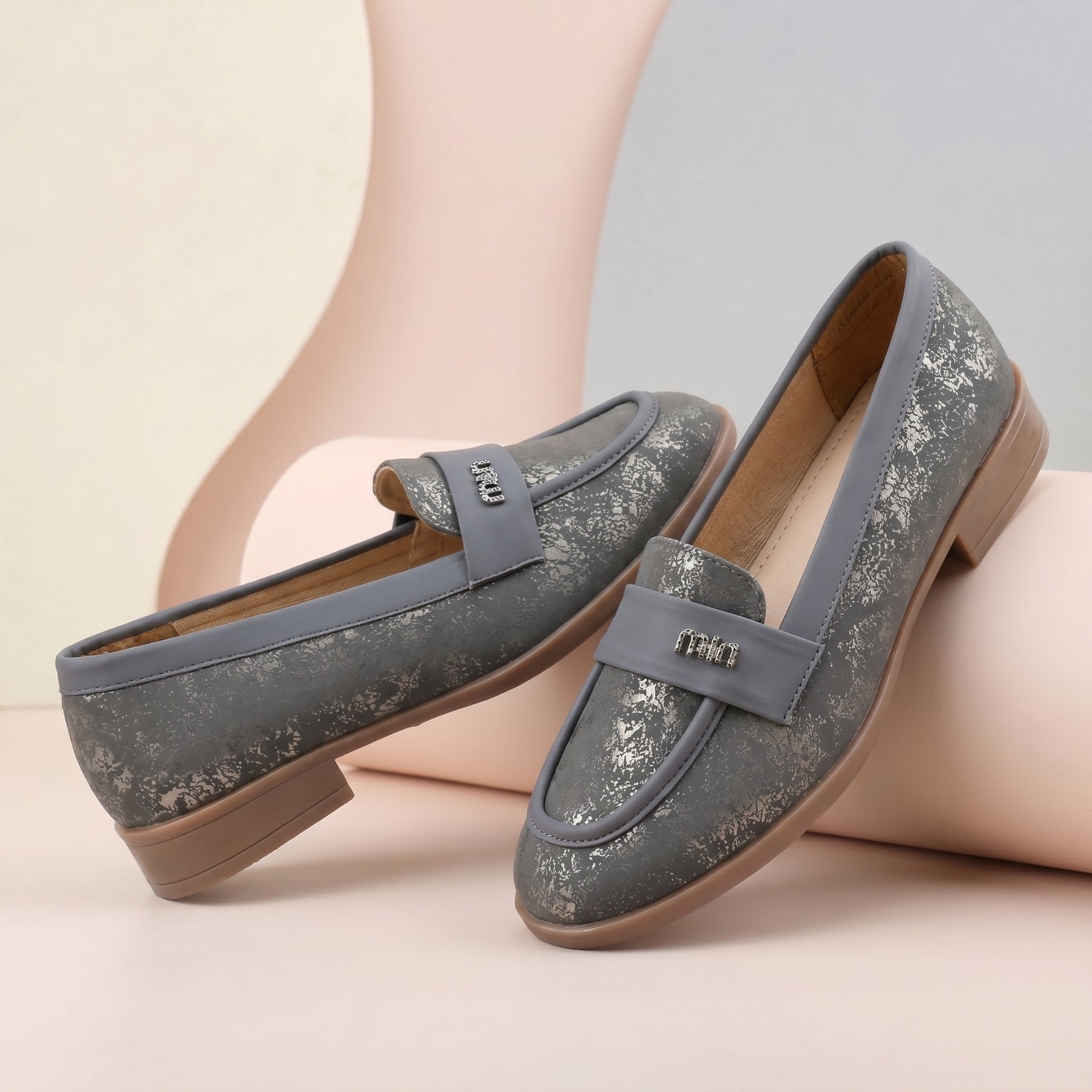 Pair of gray loafers with brown soles on a light background