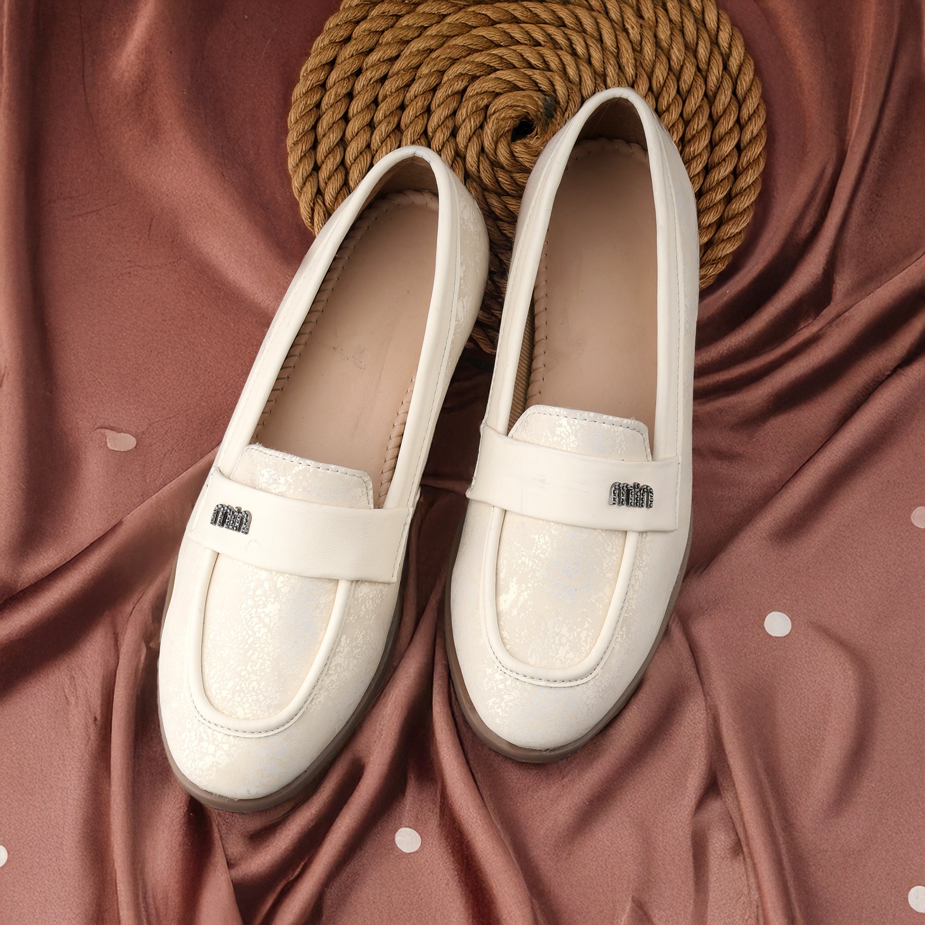 Pair of white loafers on a textured brown fabric background