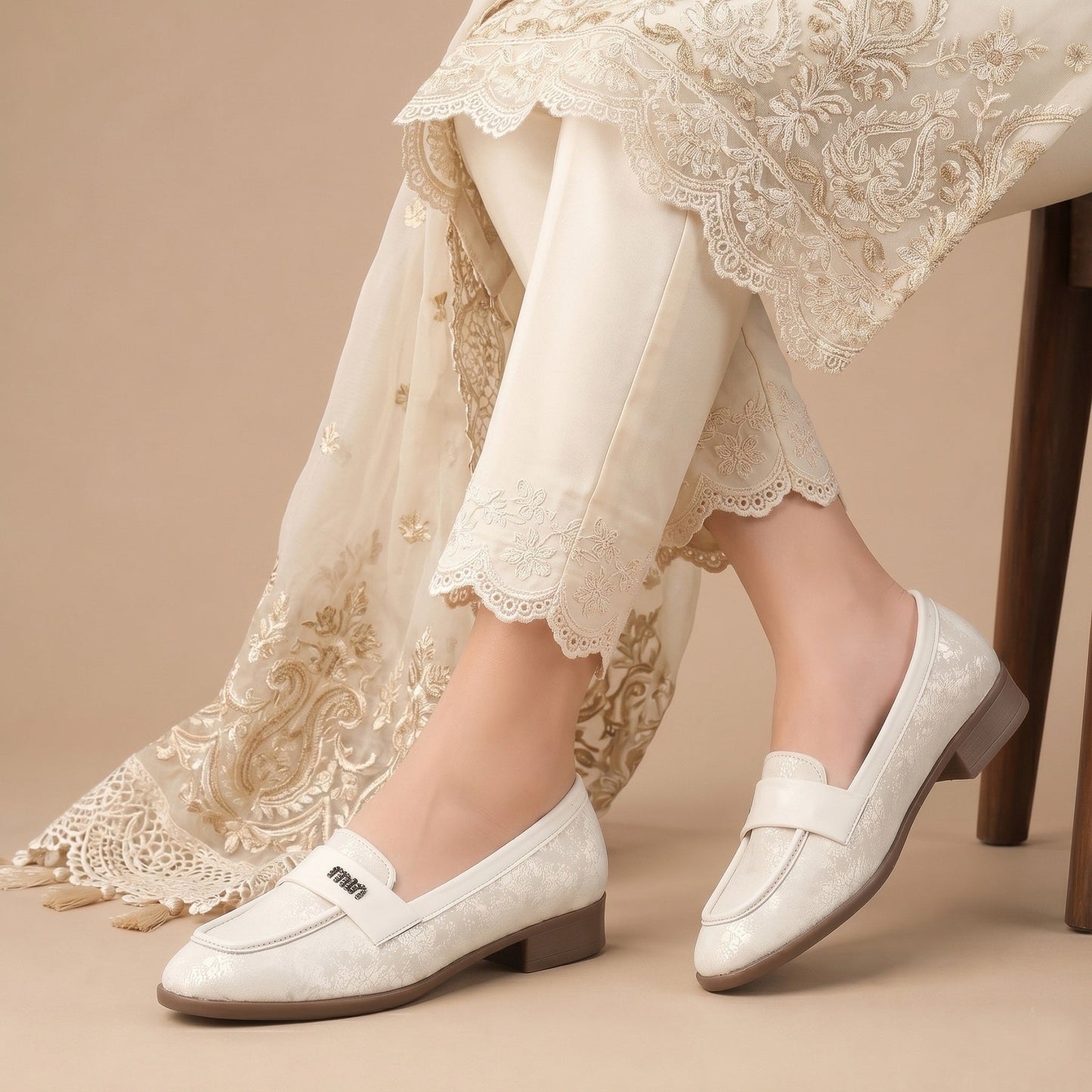 White loafers worn with a lace-trimmed dress on a beige background