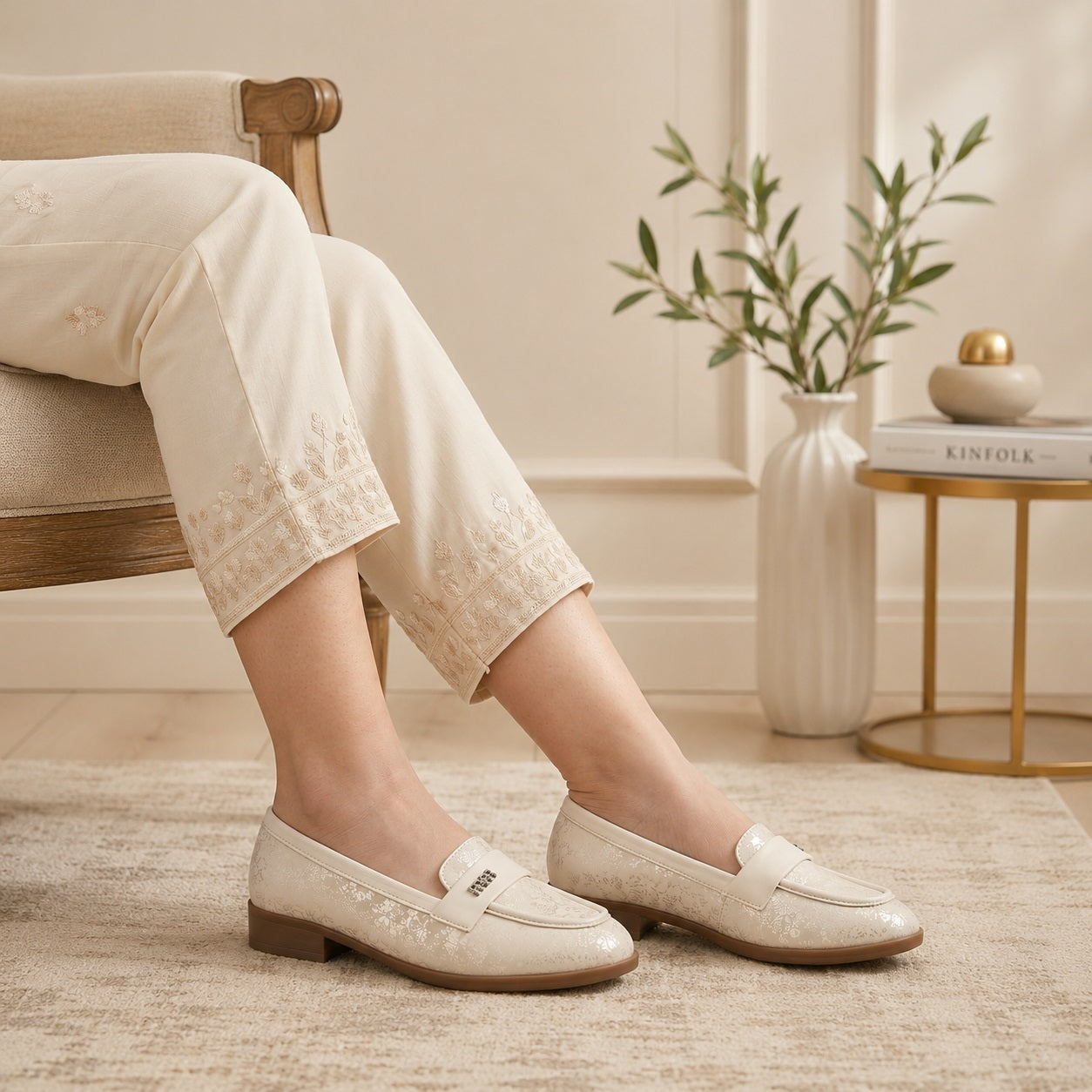 Person wearing white loafers sitting on a chair with a neutral background