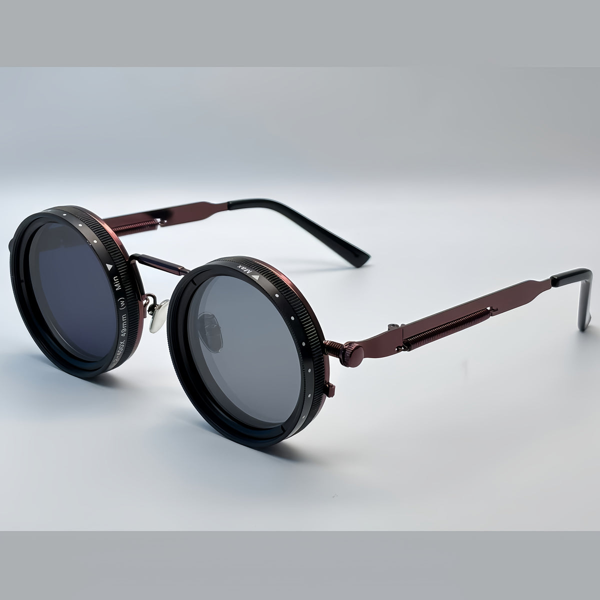 Round sunglasses with metallic frame and dark lenses on a light gray background