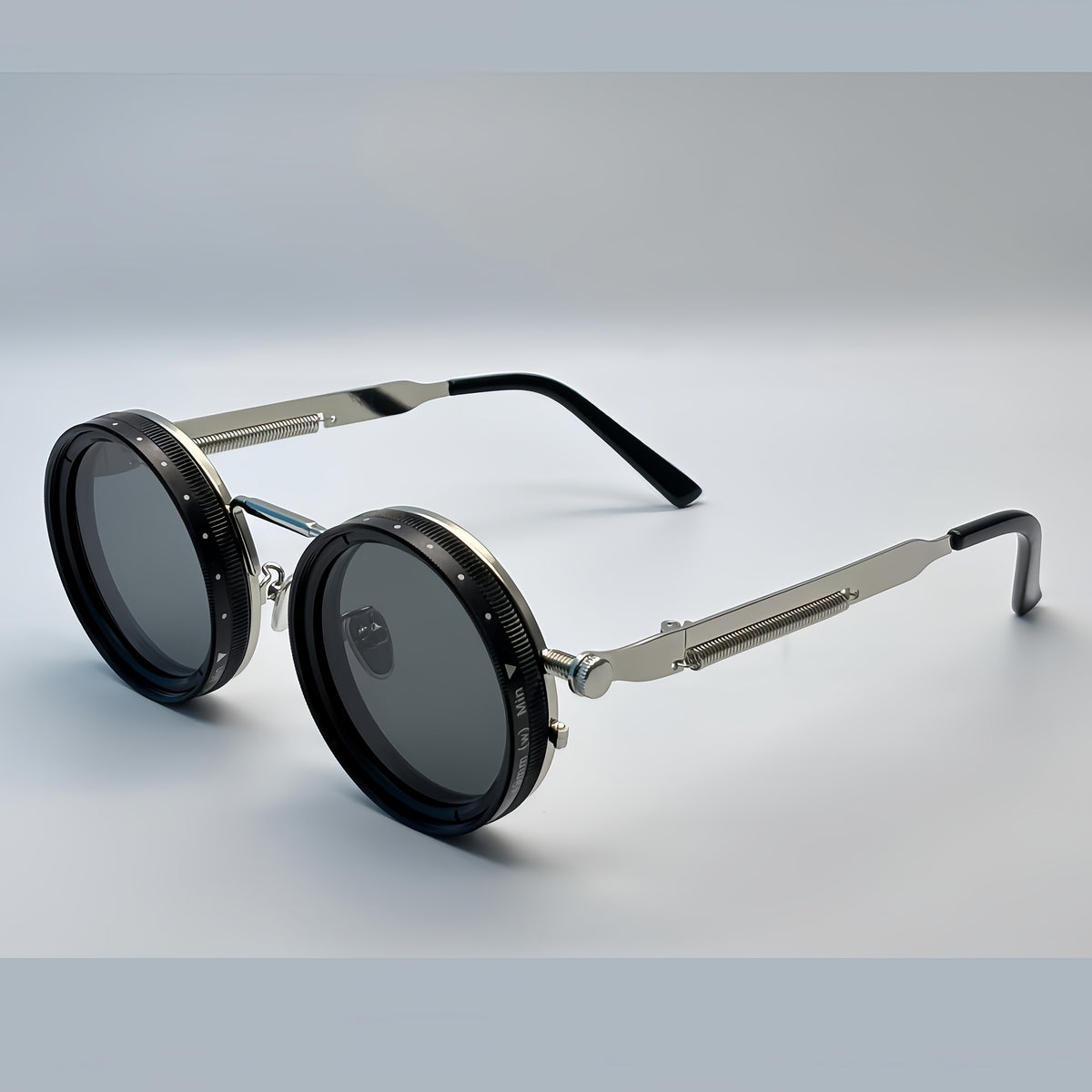 Round sunglasses with metallic frame and black lenses on a light gray background