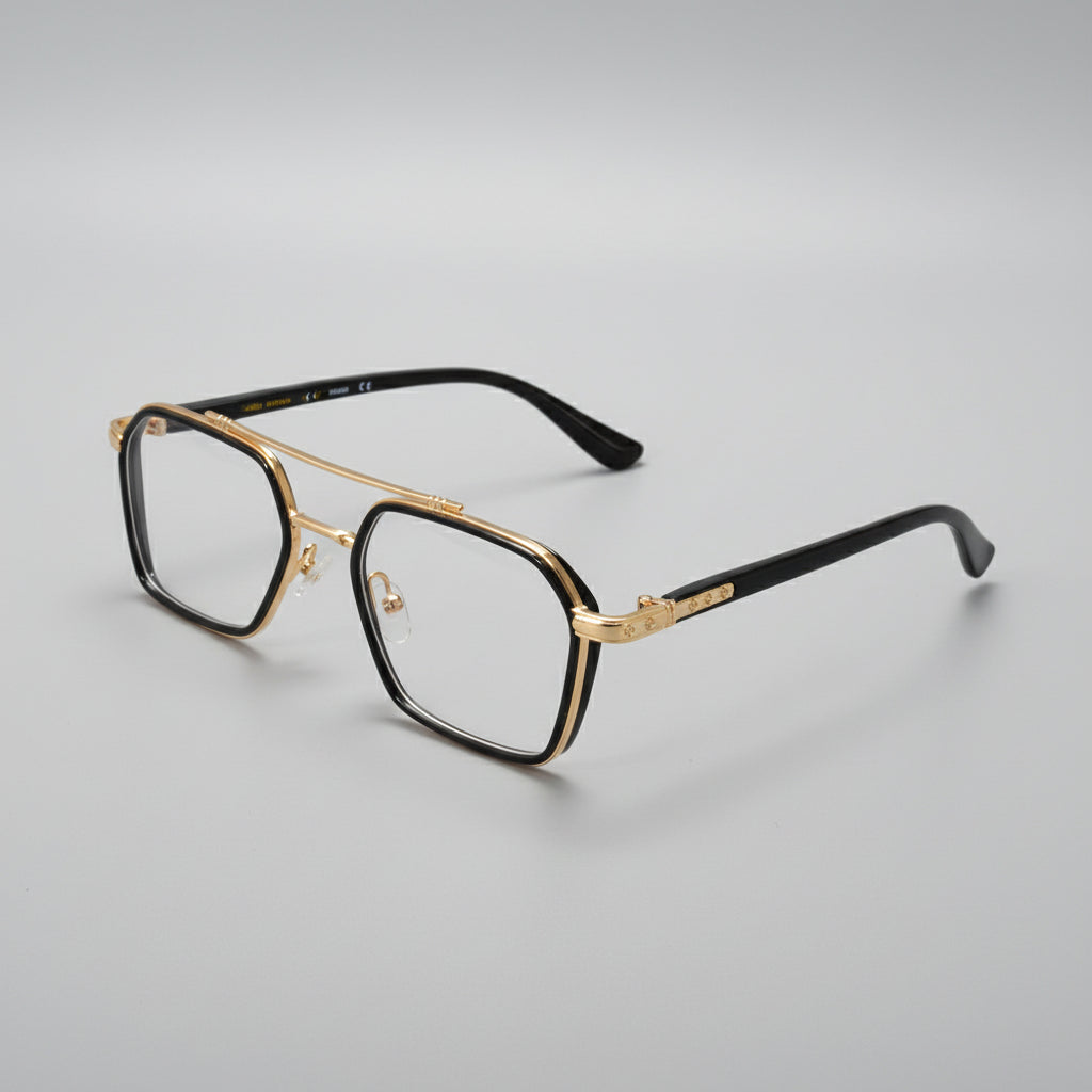 A pair of men's square aviator-style eyeglasses with a black acetate frame and gold metal double bridge, hinges, and temple accents, resting on a dark gray surface.