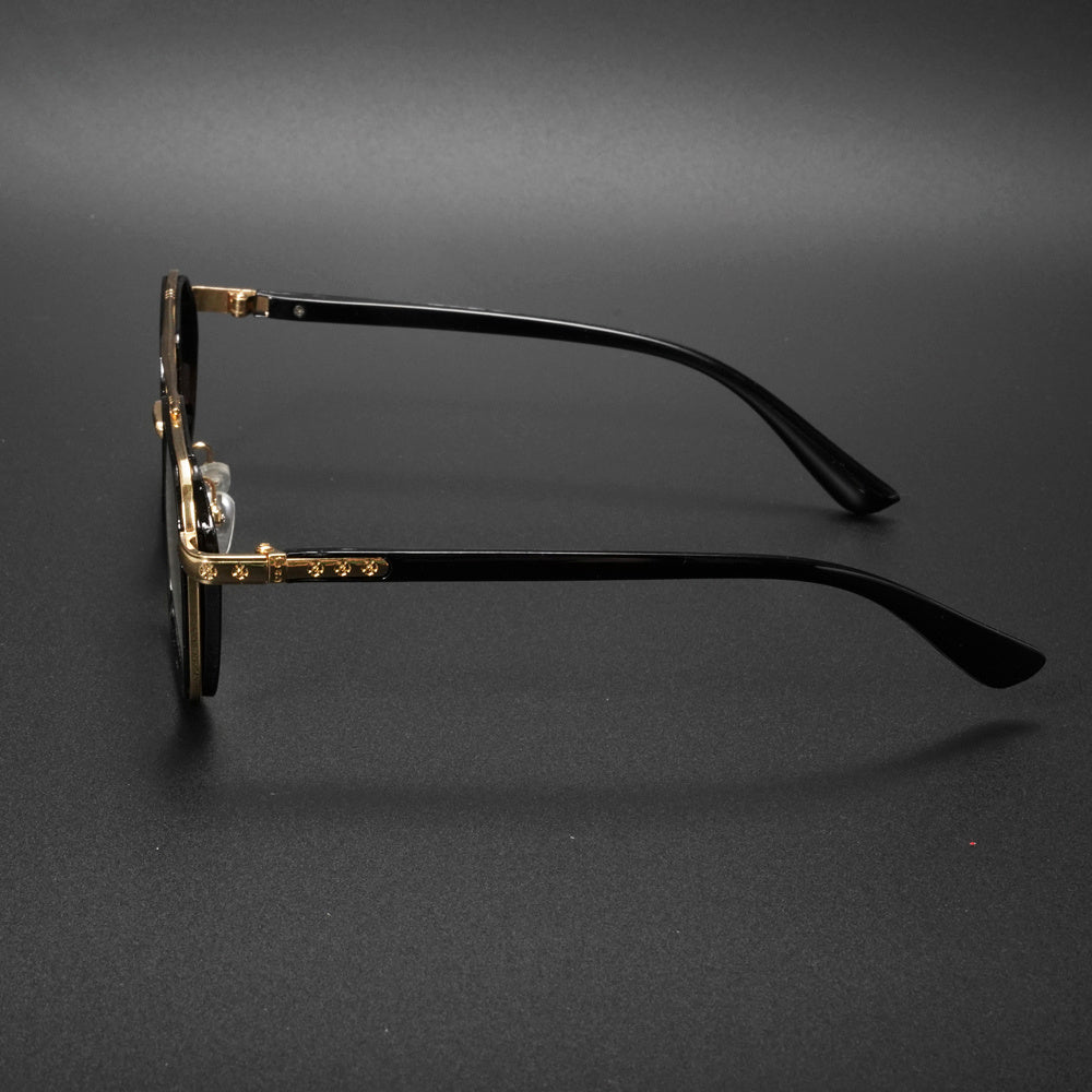 Black round-frame eyeglasses with gold metal accents on the bridge and temples, displayed on a dark gray background.