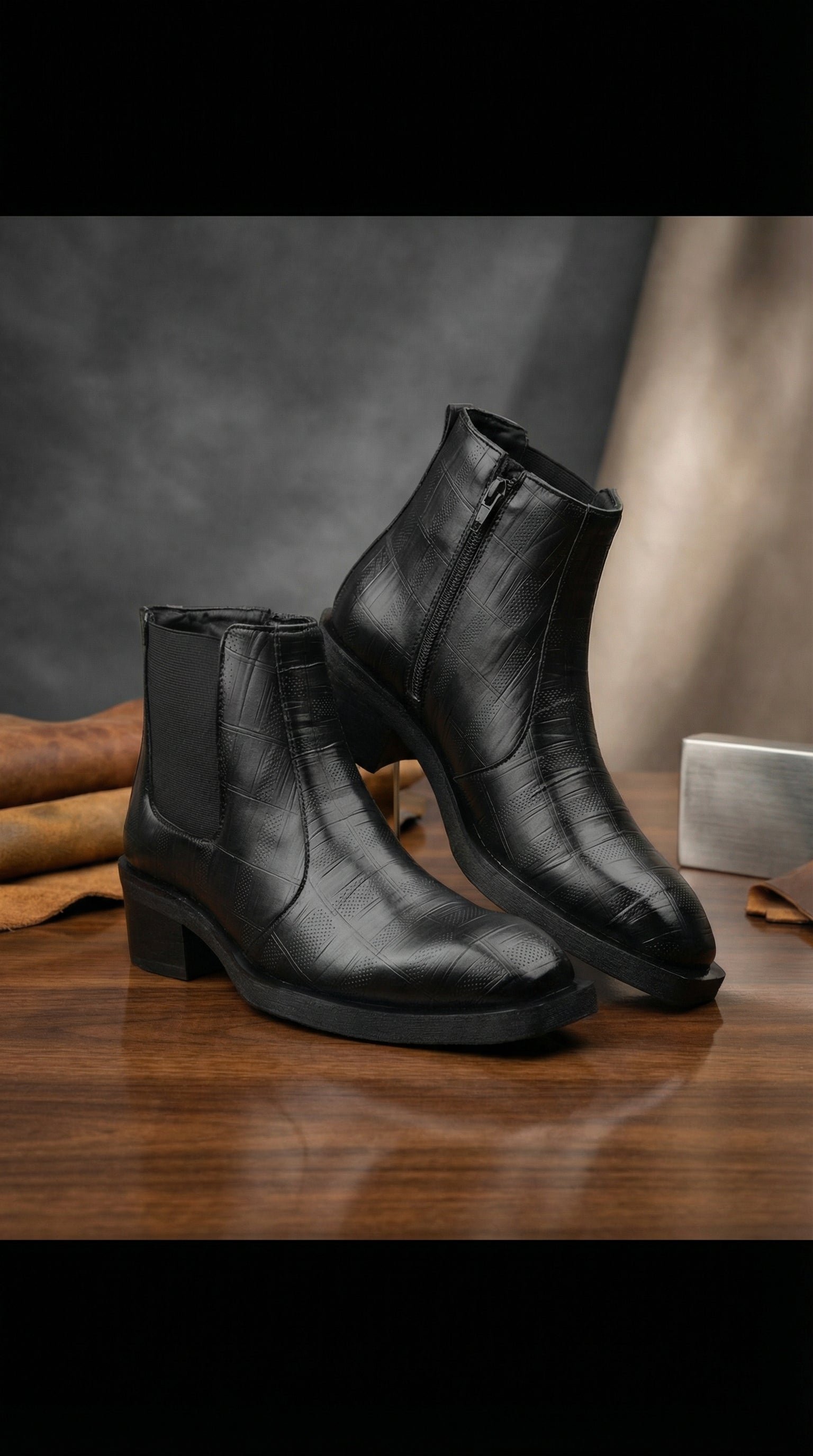Pair of black leather boots on a wooden surface with a dark background