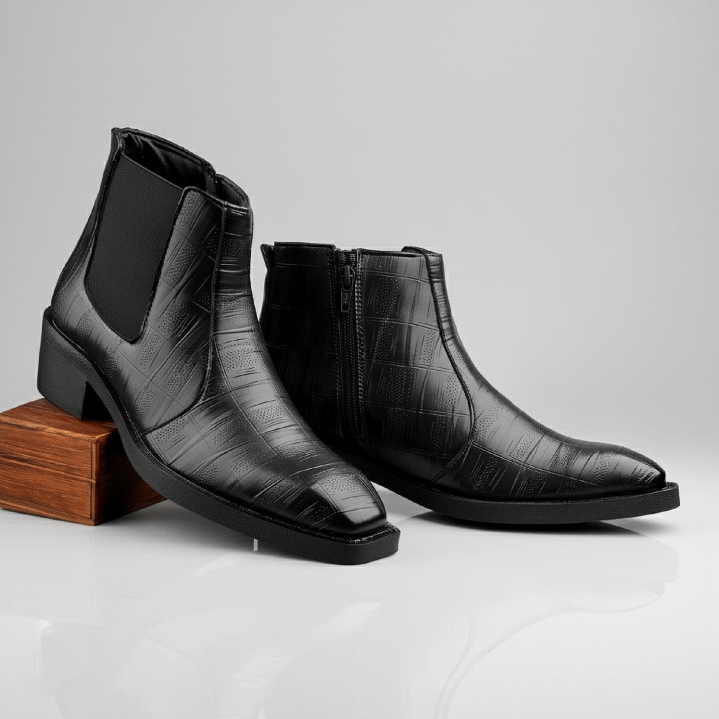 Pair of black leather boots on a light gray background