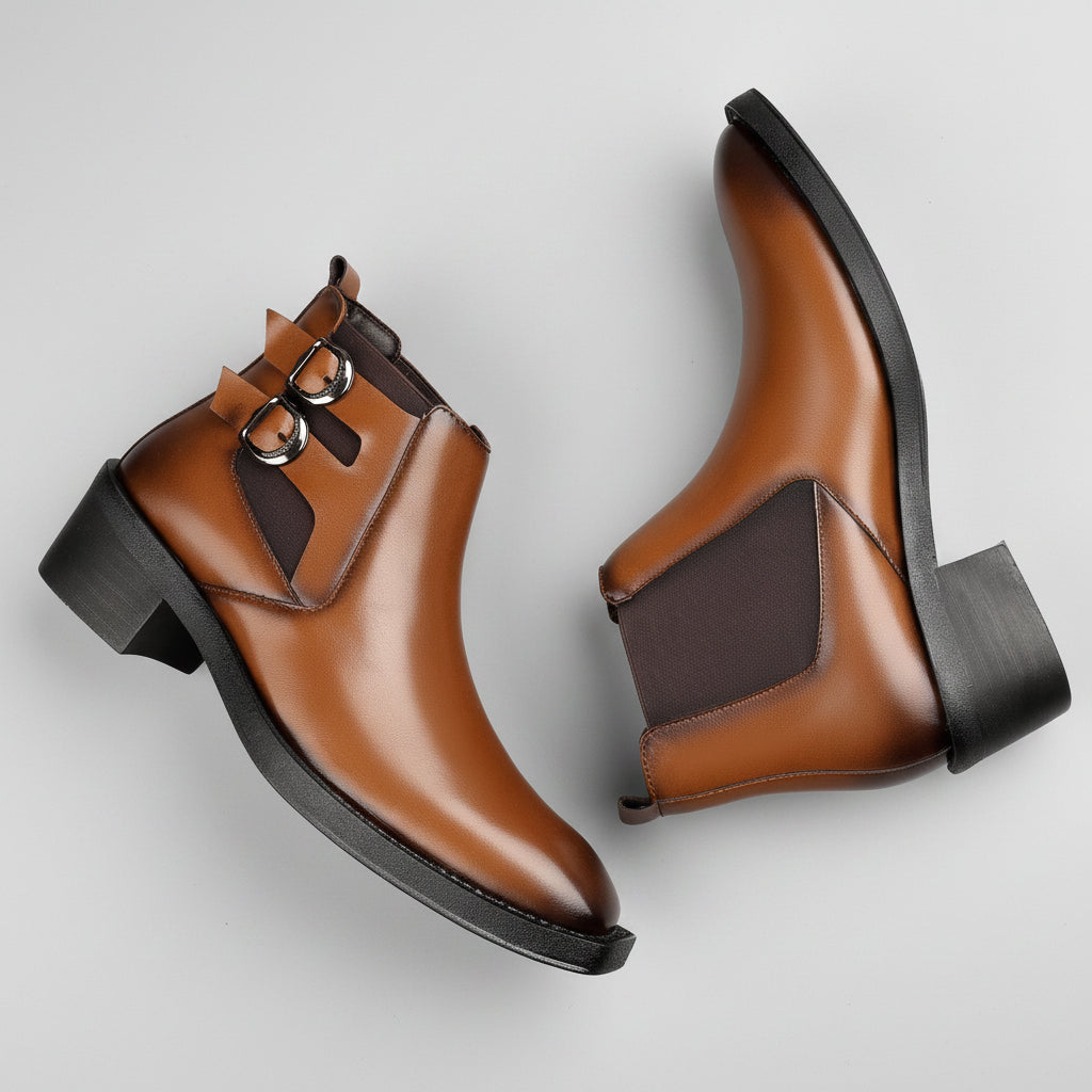 Brown leather boots with black soles on a wooden surface