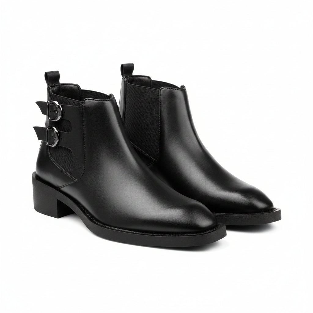 Pair of black leather ankle boots with buckles on a white background