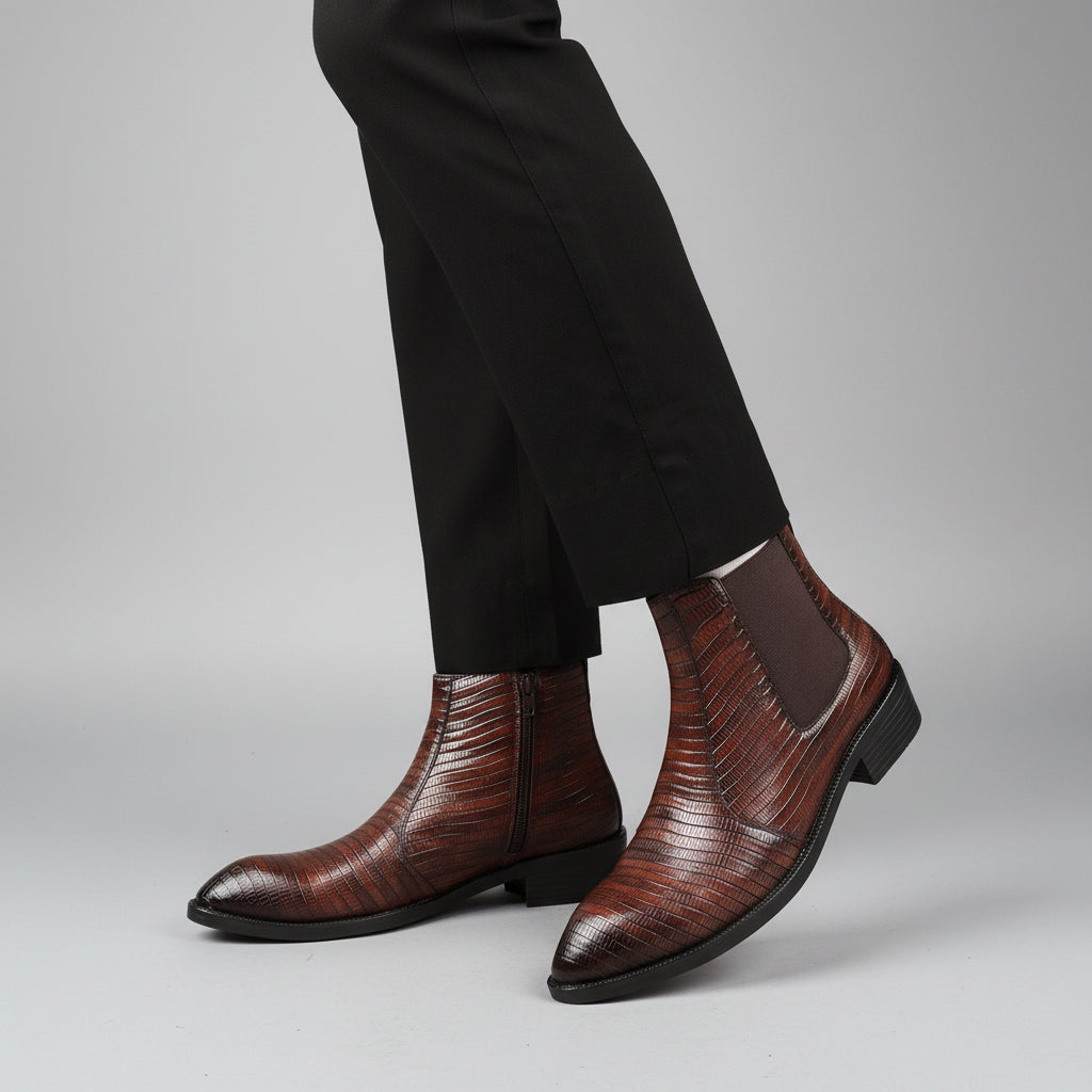 Brown leather boots worn with black pants on a neutral background