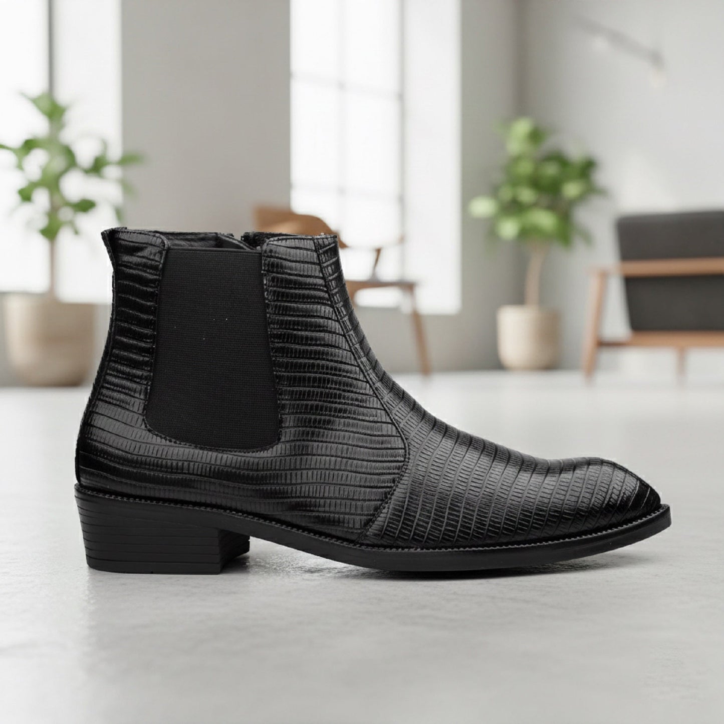 Black textured Chelsea boot on a light wooden floor with a blurred indoor background
