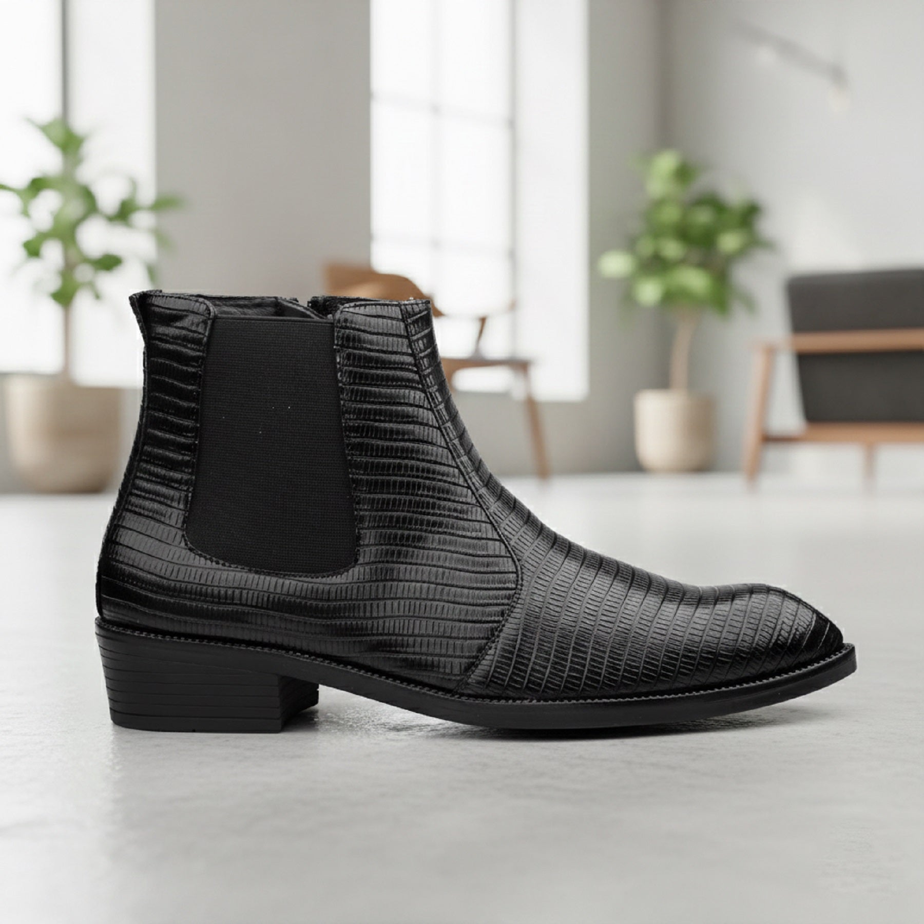 Black textured Chelsea boot on a light wooden floor with a blurred indoor background