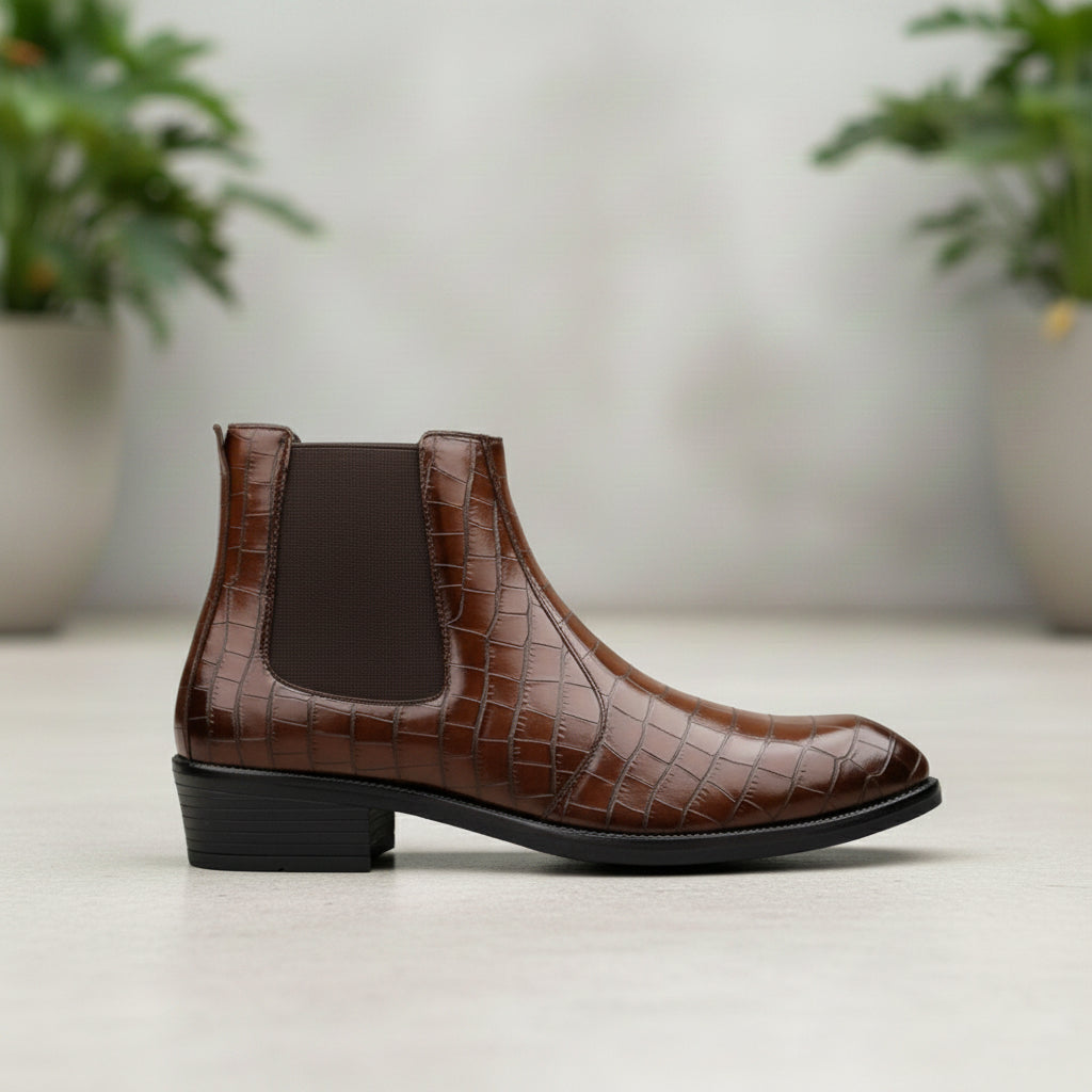Brown Chelsea boot on a light surface with a blurred plant background