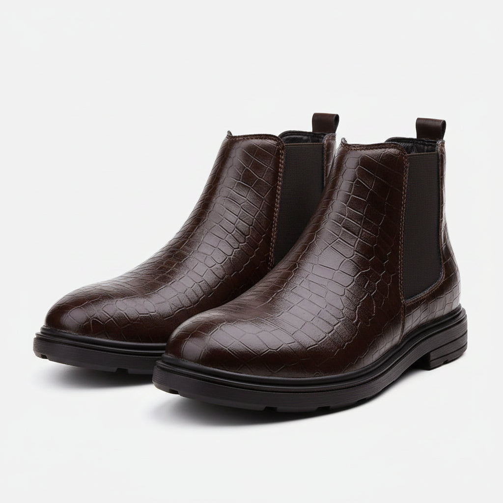 A dark brown ankle boot with a crocodile-embossed texture on the upper and black elastic side panels, shown on a white background.