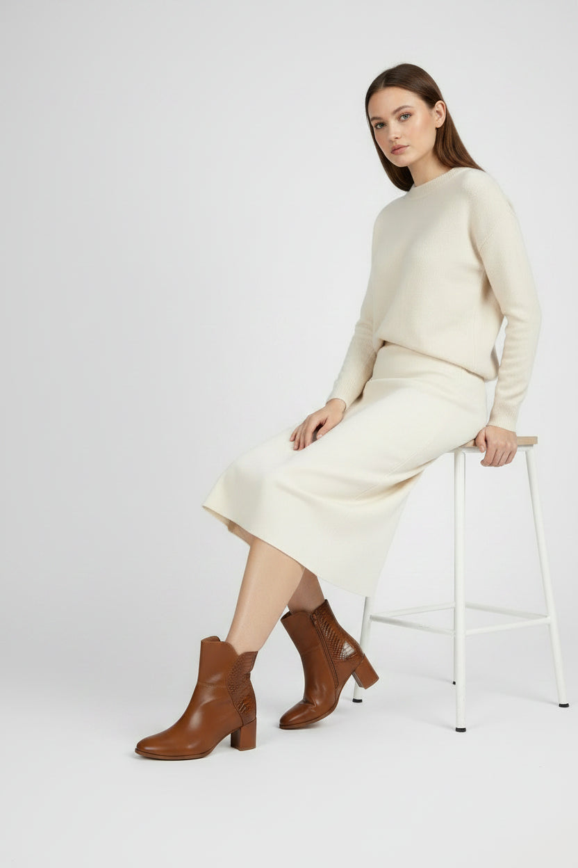 A pair of women's brown leather ankle boots with a block heel, featuring a smooth front, textured side panel, and side zippers, shown on a white background.