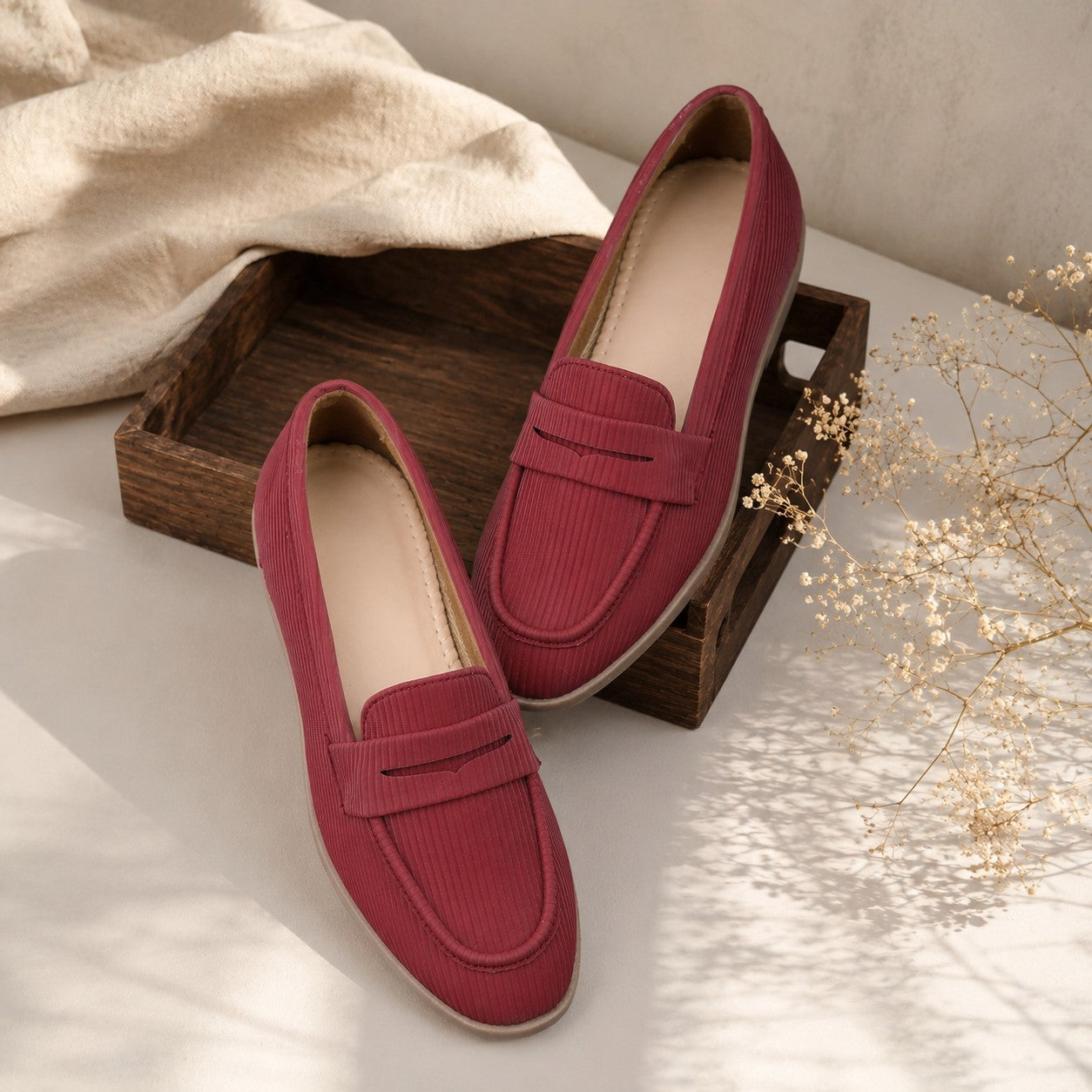 Red loafers on a wooden tray with a neutral background