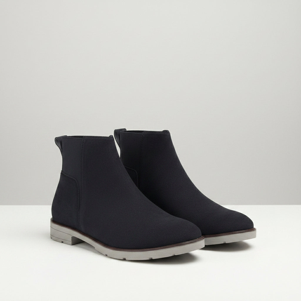 Pair of black ankle boots on a wooden surface with a neutral background