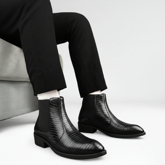 Black leather boots with a textured pattern worn by a person sitting on a couch.