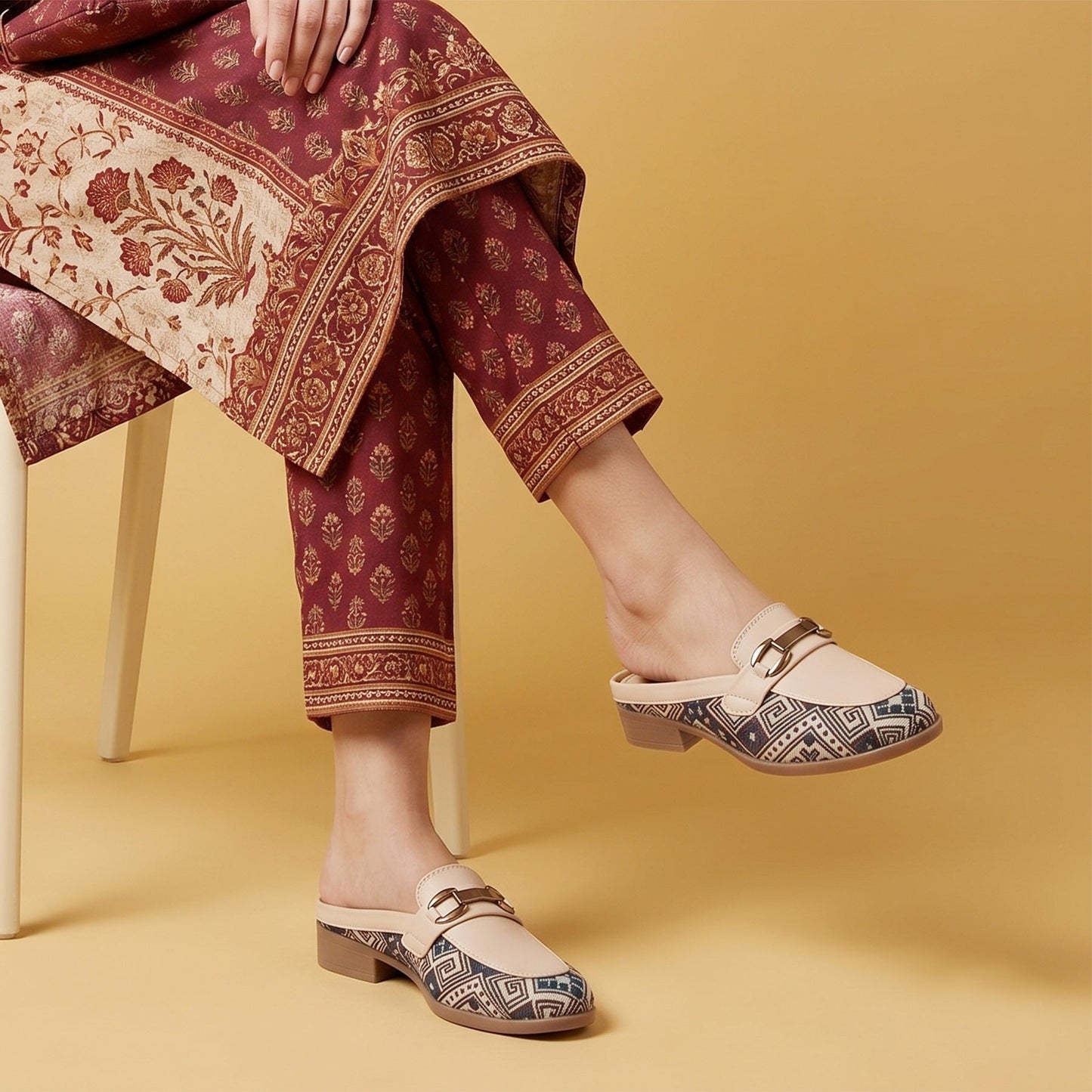 Person wearing patterned pants and decorative shoes on a yellow background