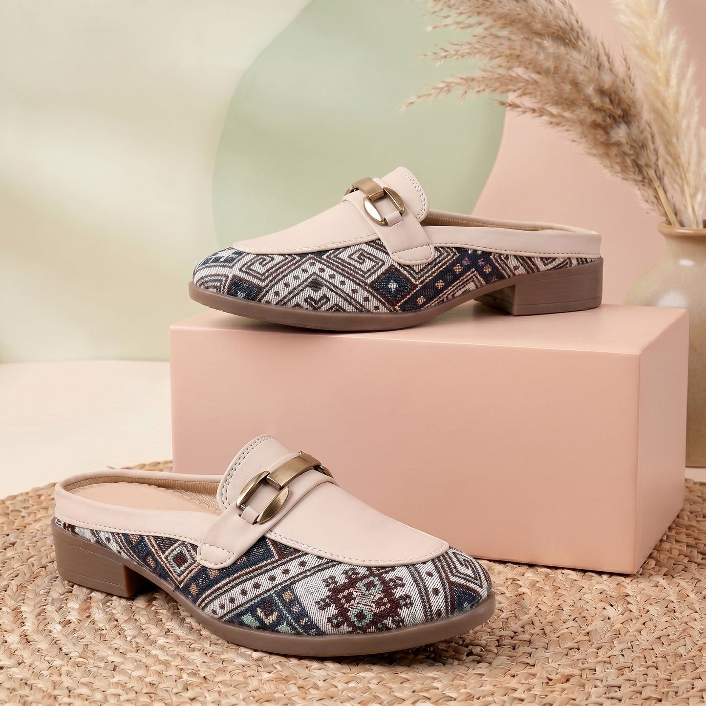 Pair of patterned loafers on a pink box with a neutral background