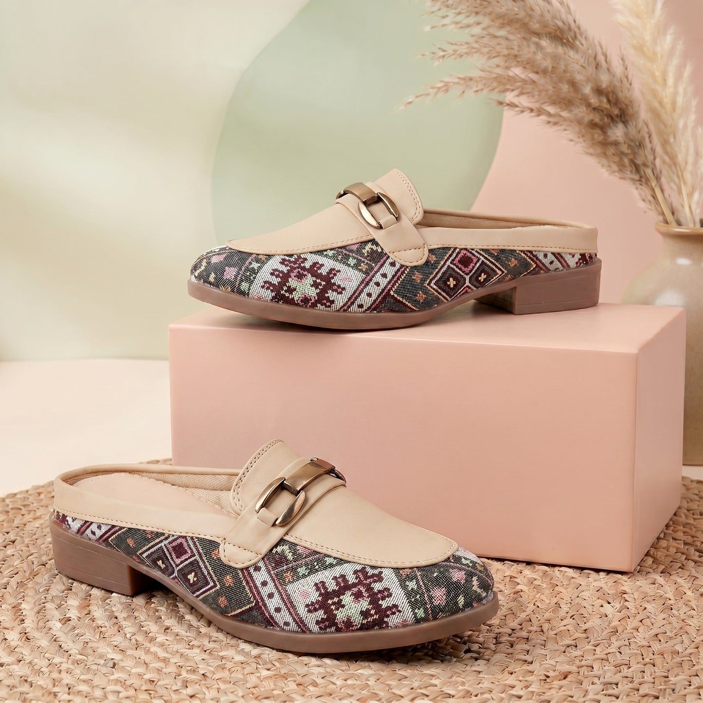 Pair of patterned loafers on a pink box with a neutral background