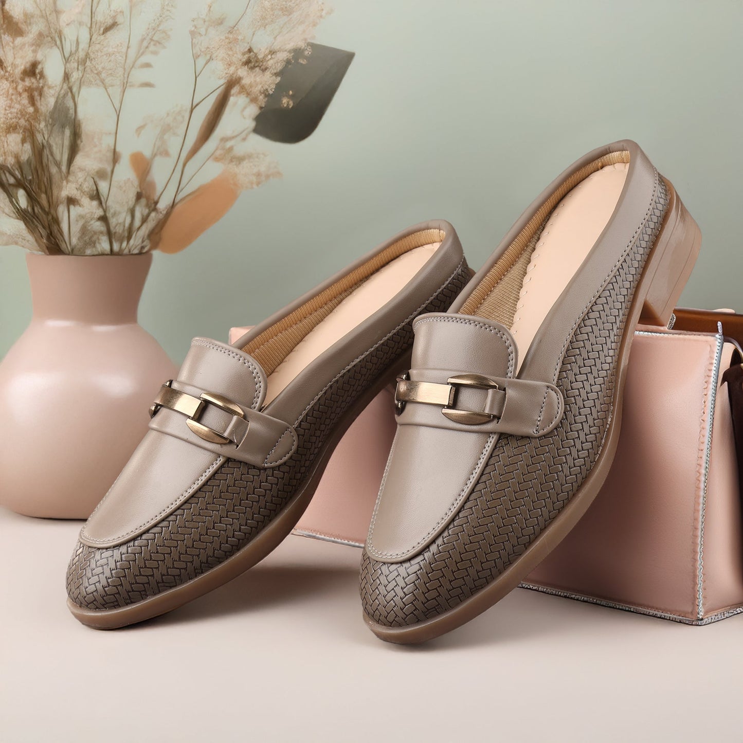 Pair of brown loafers with gold buckles on a light background