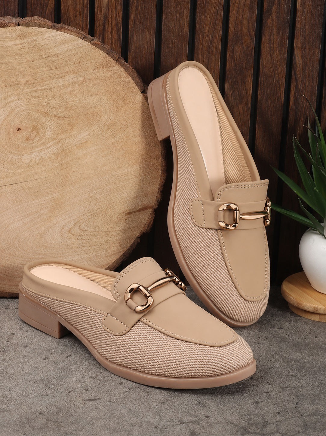 Beige loafers with gold buckles on a wooden surface