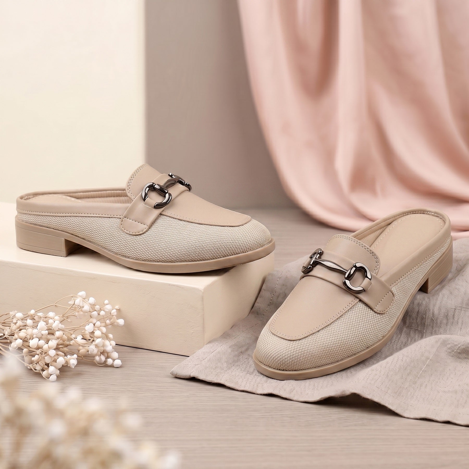 Pair of beige loafers with a decorative buckle on a neutral background