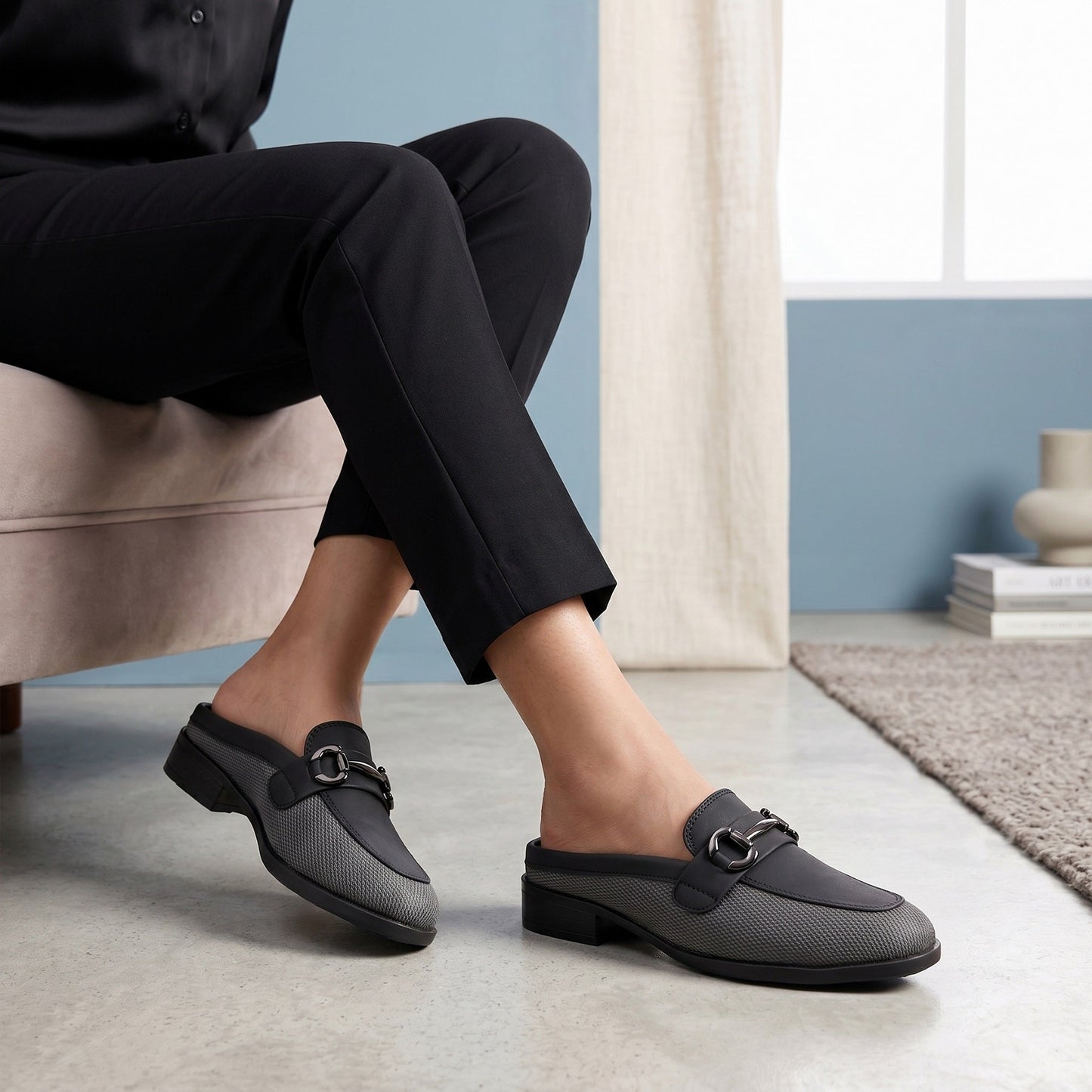 Person wearing black loafers in a home setting