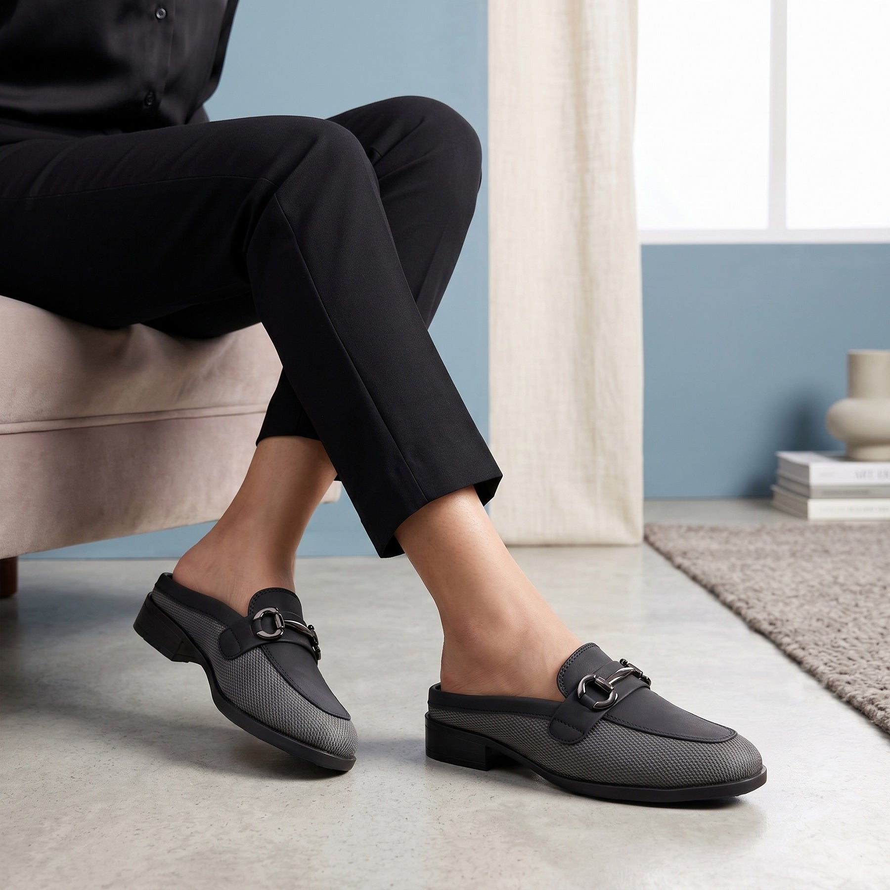 Person wearing black loafers in a home setting