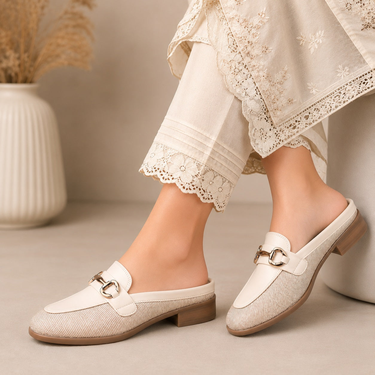 White loafers worn with light-colored pants on a neutral background