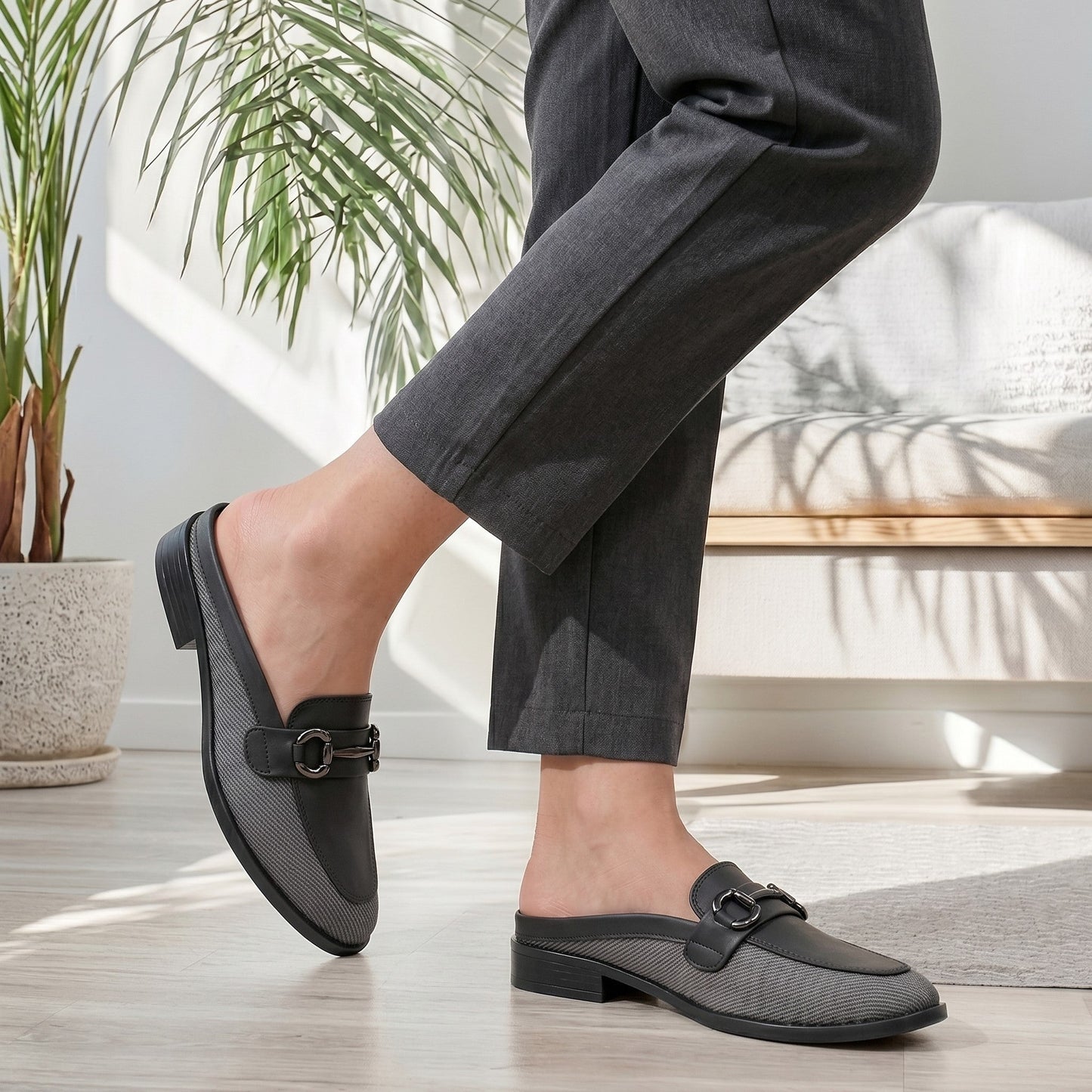Person wearing black loafers indoors with a plant and chair in the background