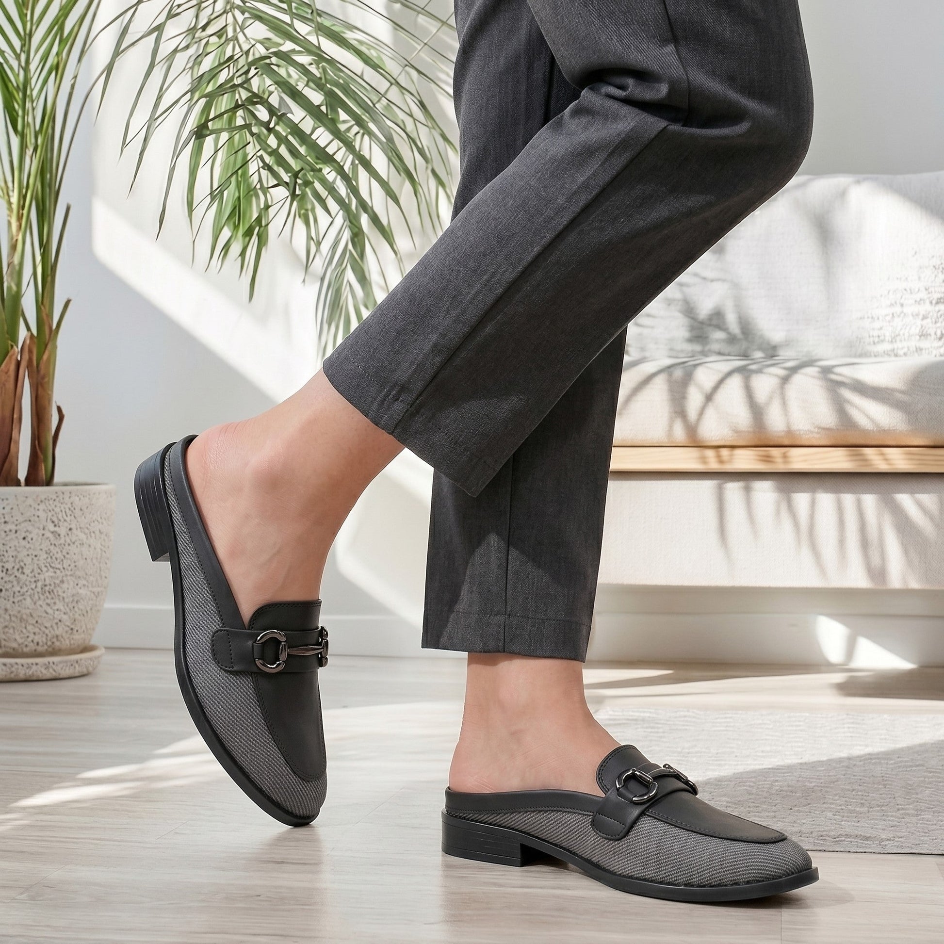 Person wearing black loafers indoors with a plant and chair in the background