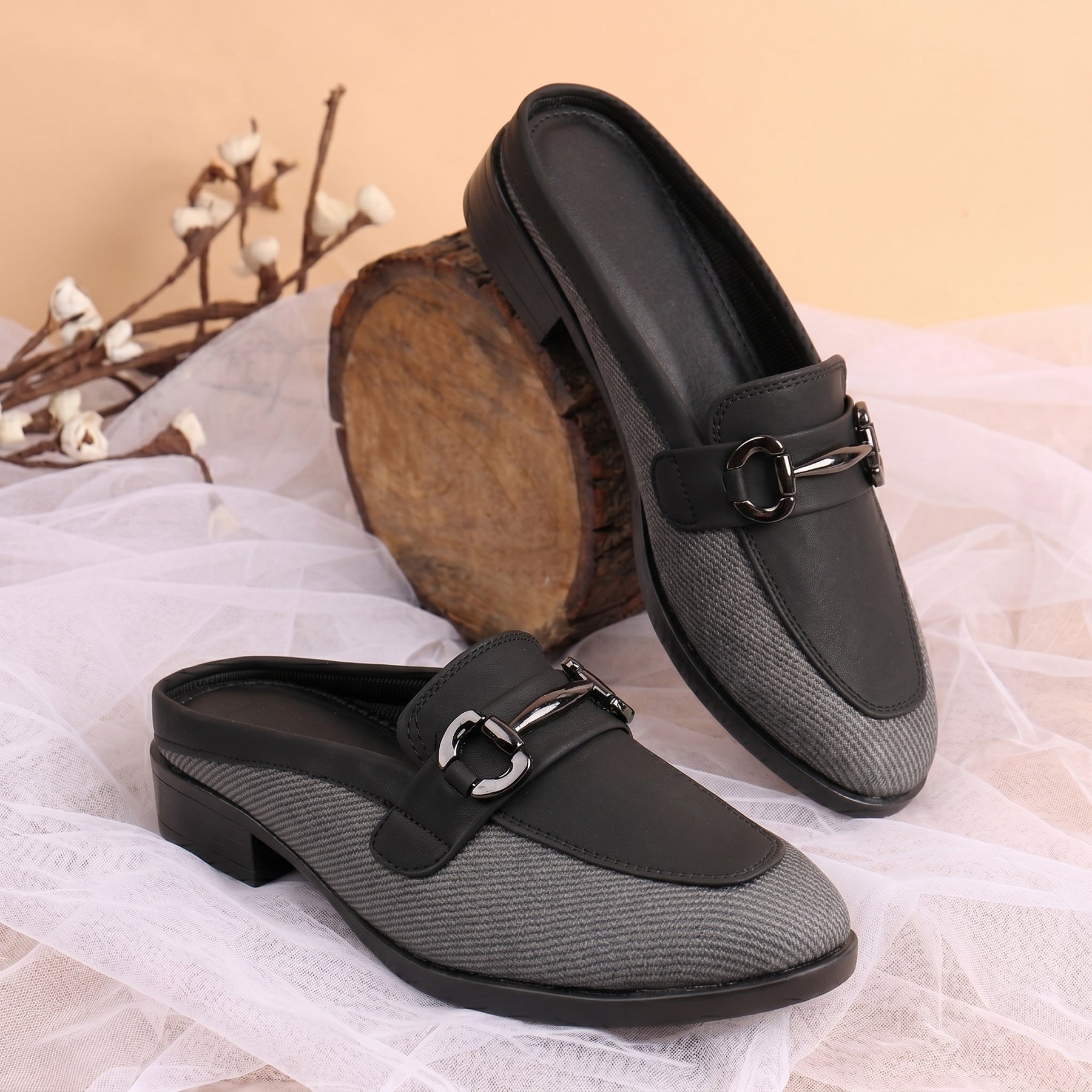 Black and gray loafers with a buckle on a white fabric background