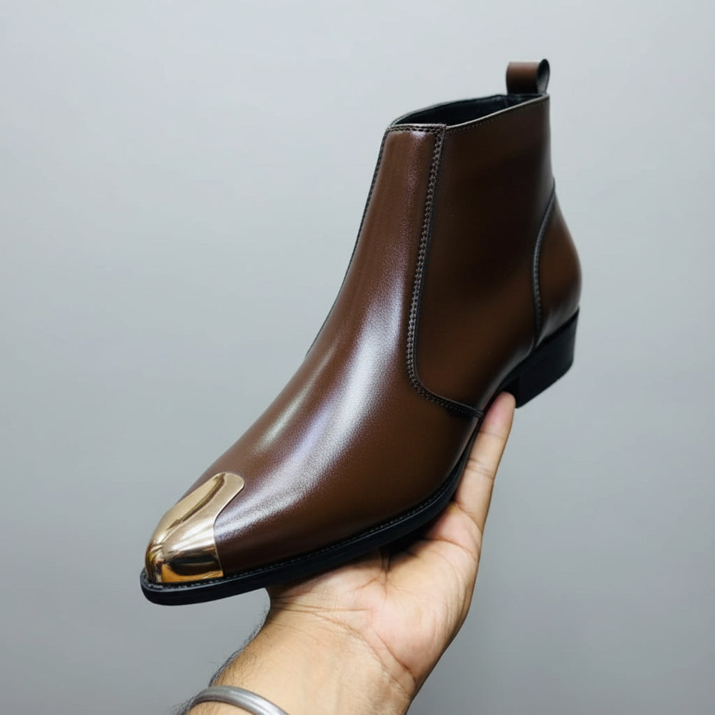 Brown leather boot with gold tip held by a hand against a yellow background