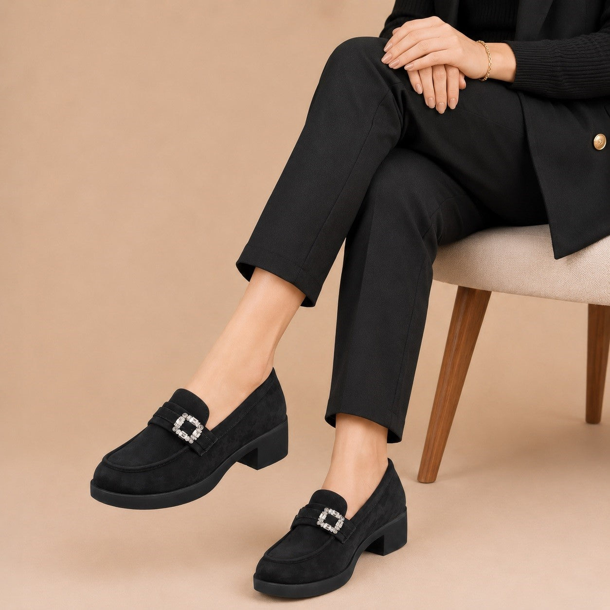 Person wearing black loafers with a beige background