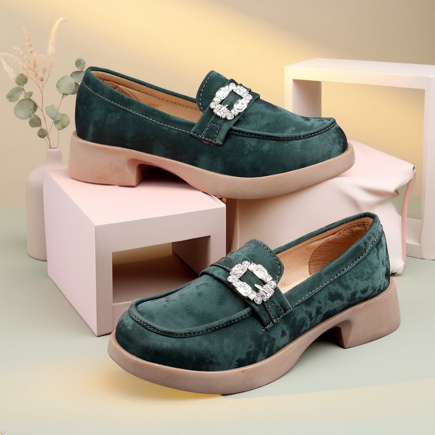 Green loafers with a decorative buckle on a light background