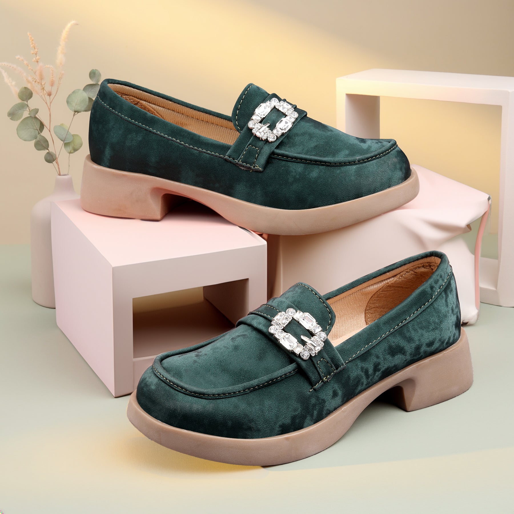 Green loafers with a decorative buckle on a light background