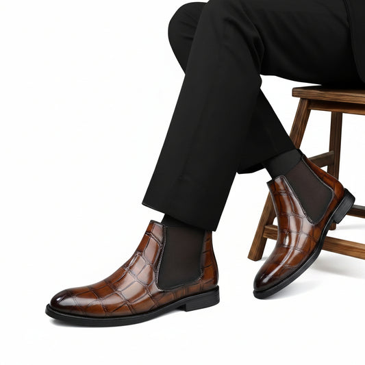 Brown leather Chelsea boots worn with black pants on a gray background